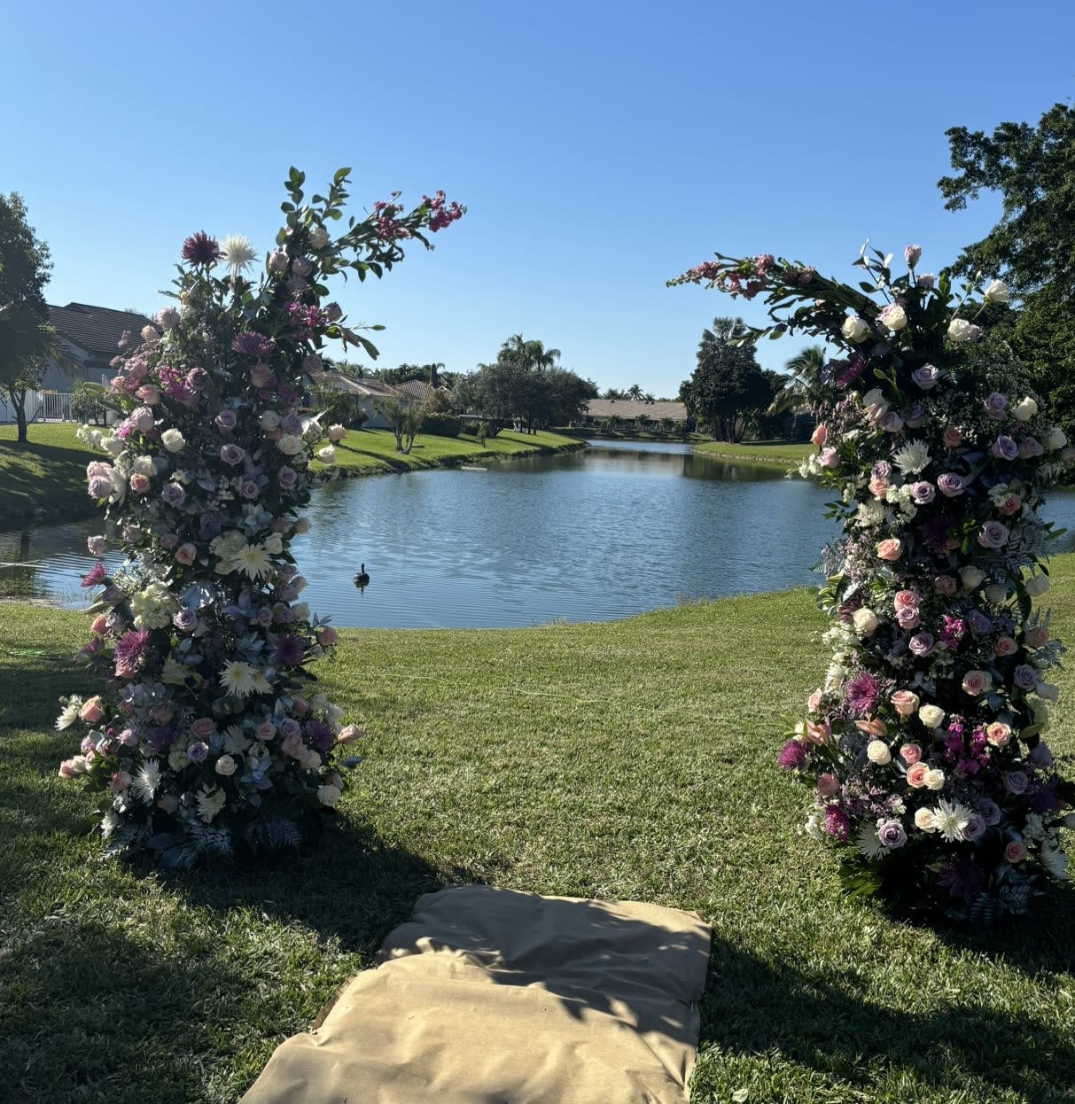 Two tall floral pillars flank a lakeside lawn