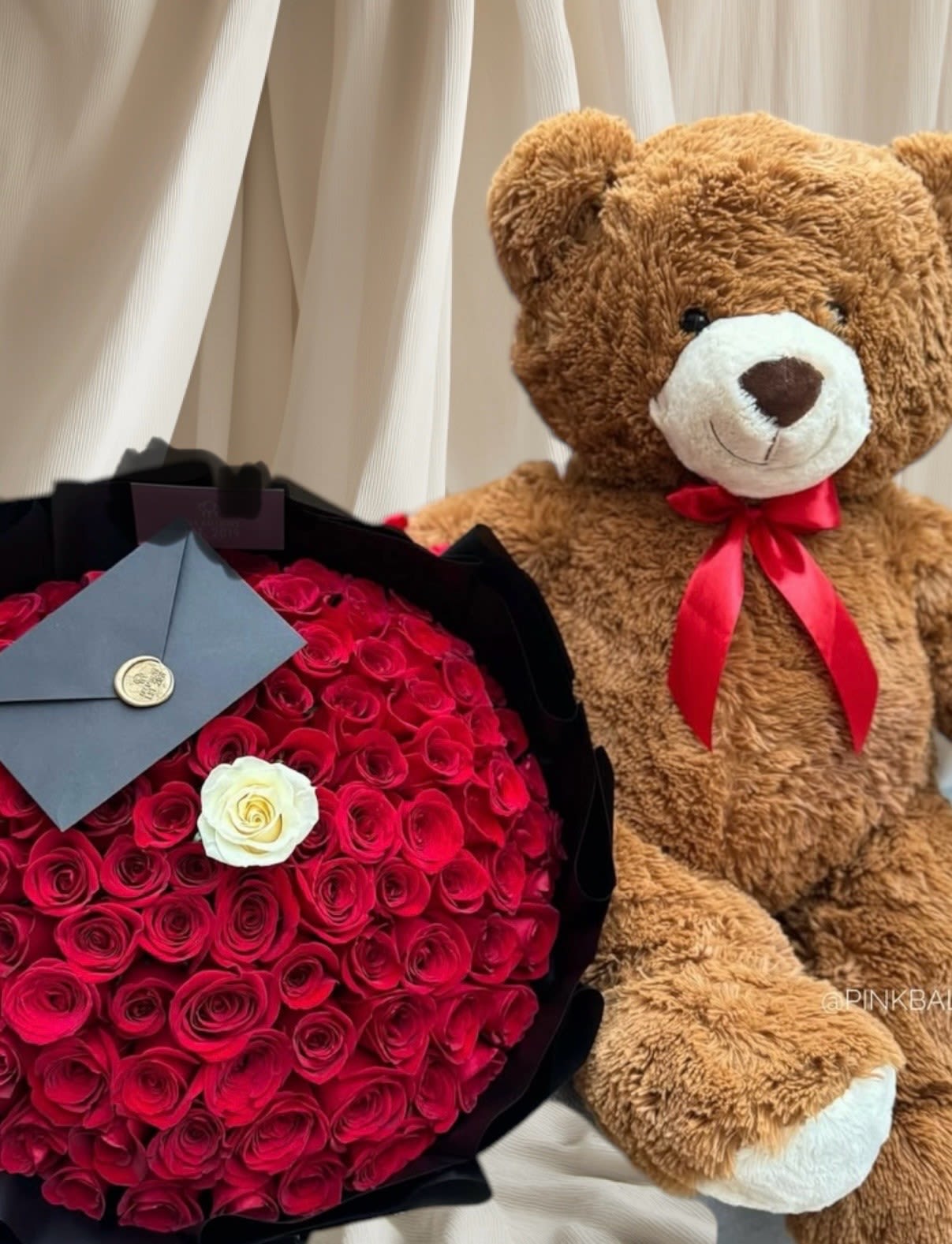 Bouquet of red roses with a white rose and a teddy bear
