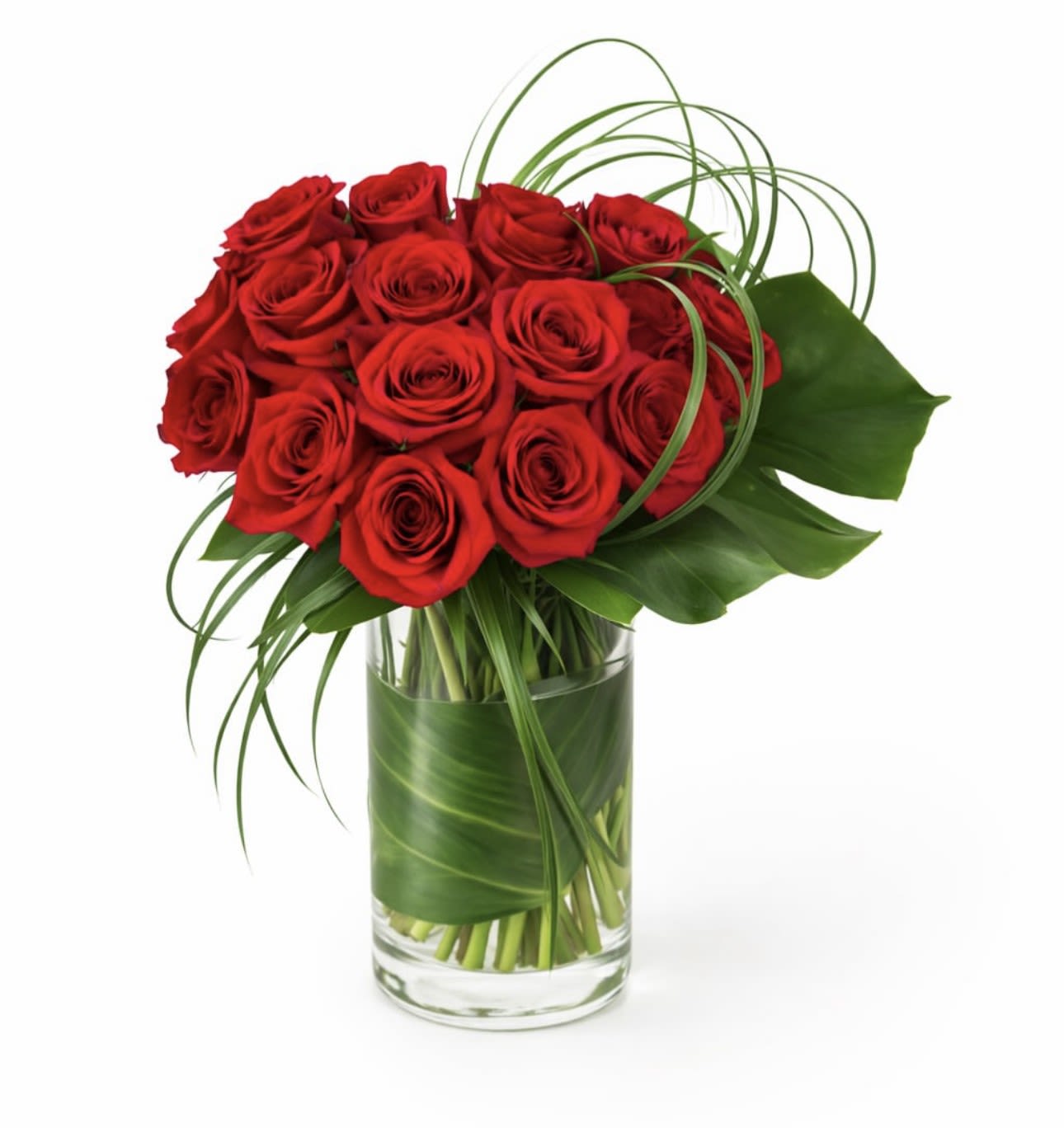 Exotic Passion Bloom - Tropical red rose floral arrangement featuring premium red roses combined with lush tropical foliage such as monstera and aspidistra, elegantly arranged in a vase. This design blends classic romance with exotic beauty, creating a vibrant and sophisticated piece that transports you straight to a tropical paradise filled with freshness and natural elegance.