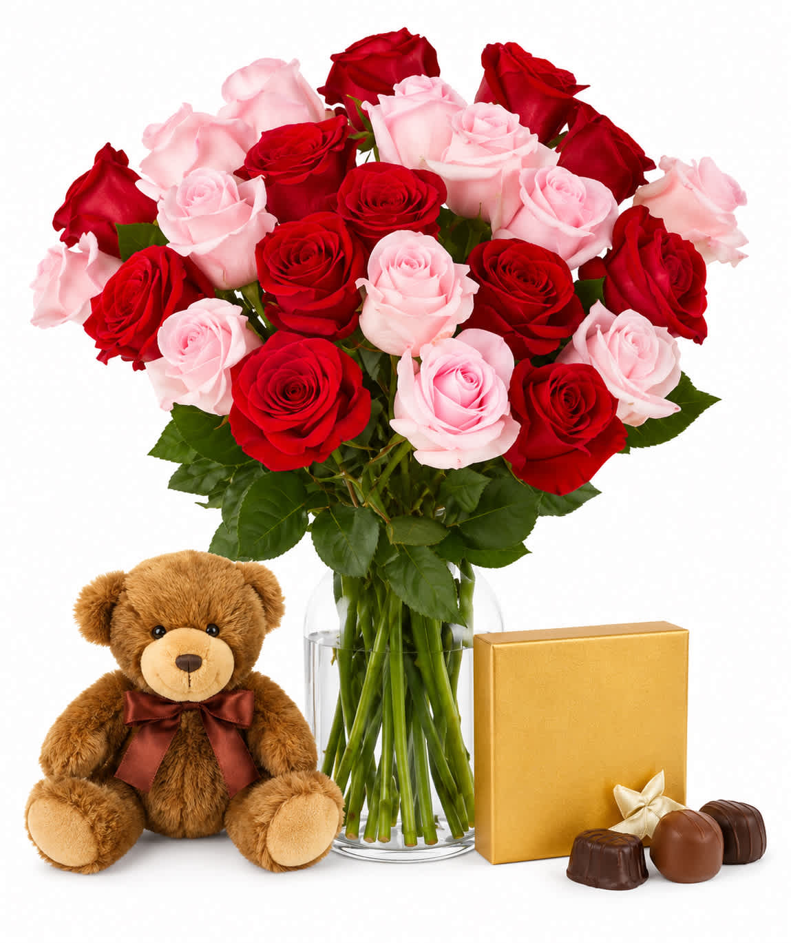 Bouquet of red and pink roses in a glass vase with a teddy bear and chocolates