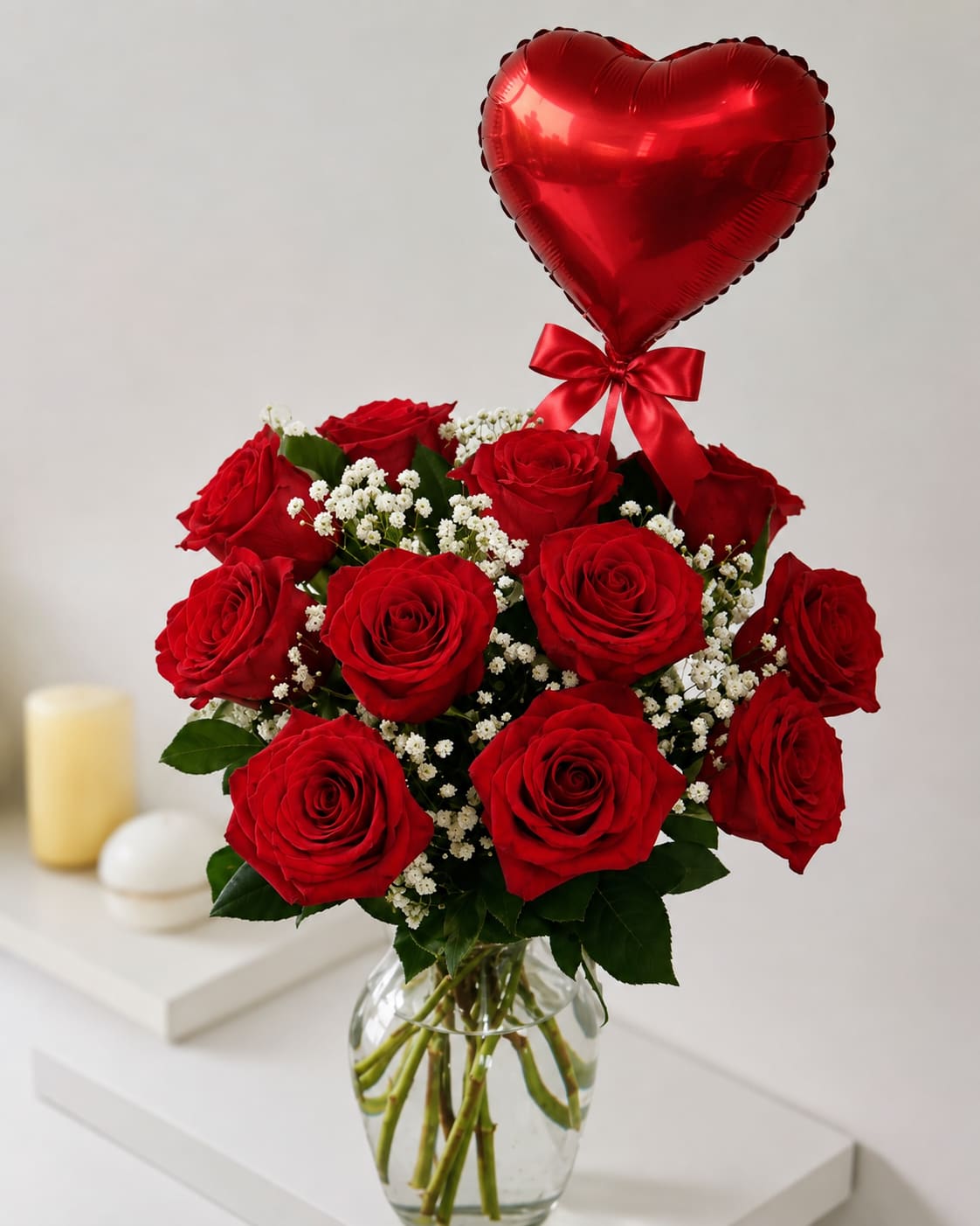 Red roses in a glass vase with a red heart balloon