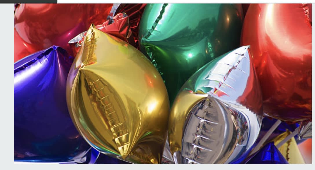 Cluster of shiny metallic balloons in red, gold, blue, green, and silver