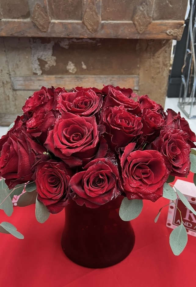Bouquet of red roses in a dark vase with eucalyptus accents
