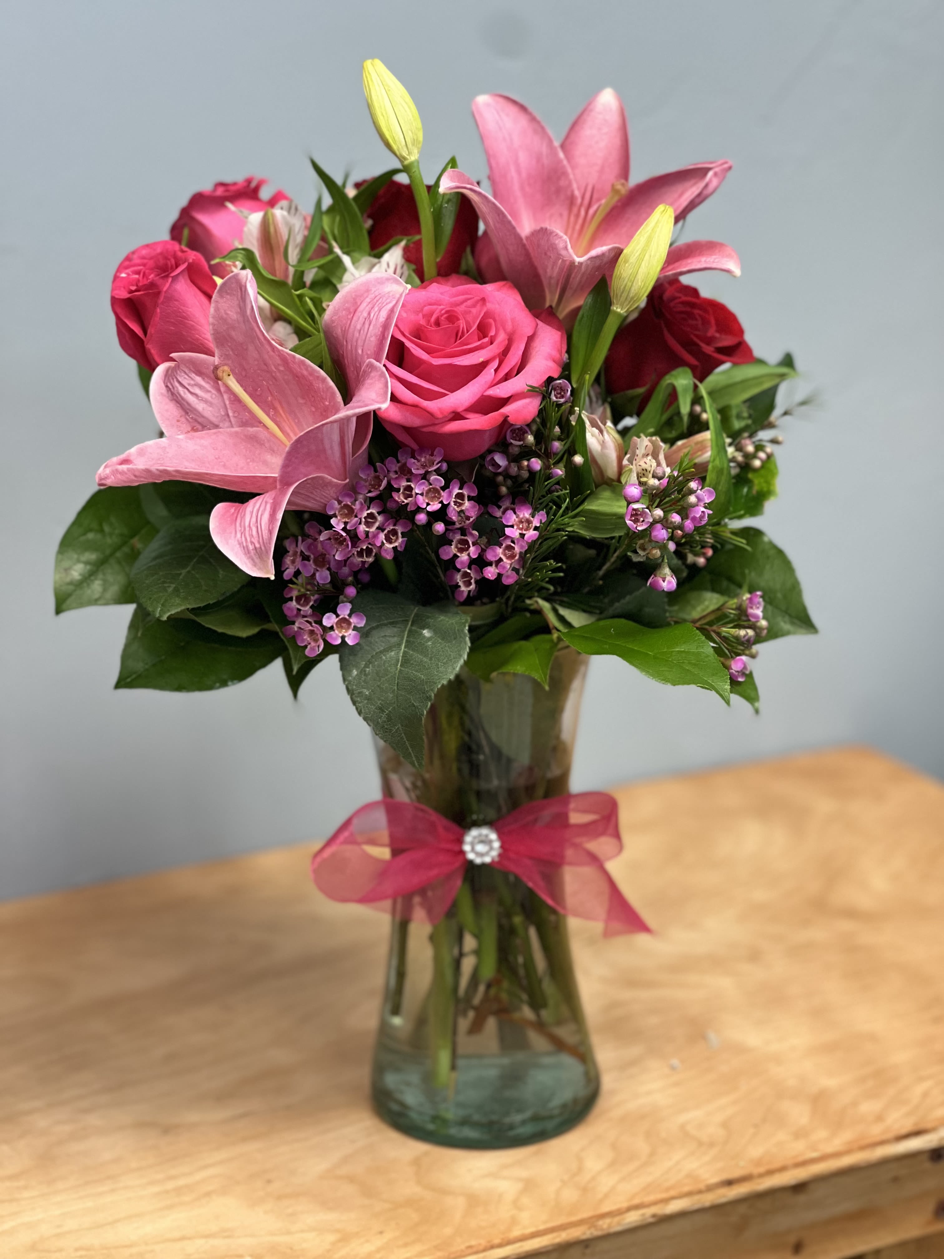 Rose &amp; Lily Celebration - Send stunning flowers to celebrate any occasion! With classic floral colors including red roses and pink lilies, the Rose and Lily Joy is a wonderful gift to send to a friend or family member for a birthday, get well or anniversary. The floral artist creates the Rose and Lily bouquet with red roses, pink roses, pink lilies, pink alstroemeria and purple waxflower.  Some Lilies may be fully closed due to freshness.   Includes: • Pink Asiatic Lilies • Pink and Red Roses • Purple Waxflowers • Alstroemeria • Glass Vase    Substitutions may be necessary to ensure your arrangement or specialty gift is delivered in a timely manner and depending on availability.  Substitution Policy Substitutions may be necessary to ensure your arrangement is delivered in a timely manner. The utmost care and attention is given to your order to ensure that it is as similar as possible to the requested item.  Flowers In arrangements of assorted flowers, the colors shown online will be used if at all possible, even if this means substituting other kinds of flowers of equal or greater value. For one-of-a-kind flower arrangements, such as all roses or all lilies, we will make every attempt to match the flower type, but may substitute with another color. If the floral container shown online is not available, a similar container will be used.