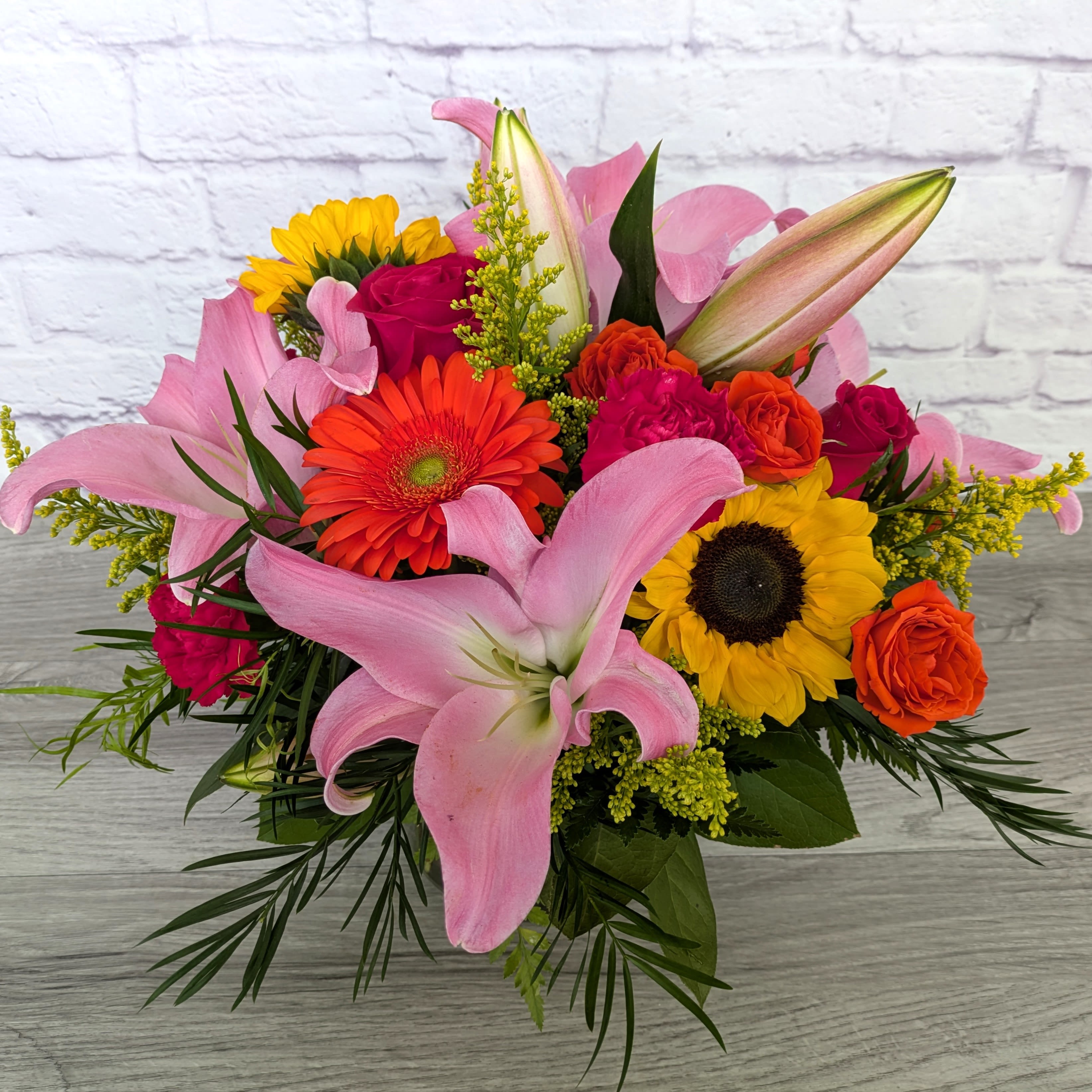A Summer To Remember - A Summer To Remember is A Ladybug Floral exclusive bouquet. This bouquet includes either stargazer lilies or pink oriental lilies, sunflowers, roses, spray roses, gerbera daisies, carnations and solidago . Featured in a classic 6” bell jar.  Orientation: All Around 15” Tall 19” Wide  