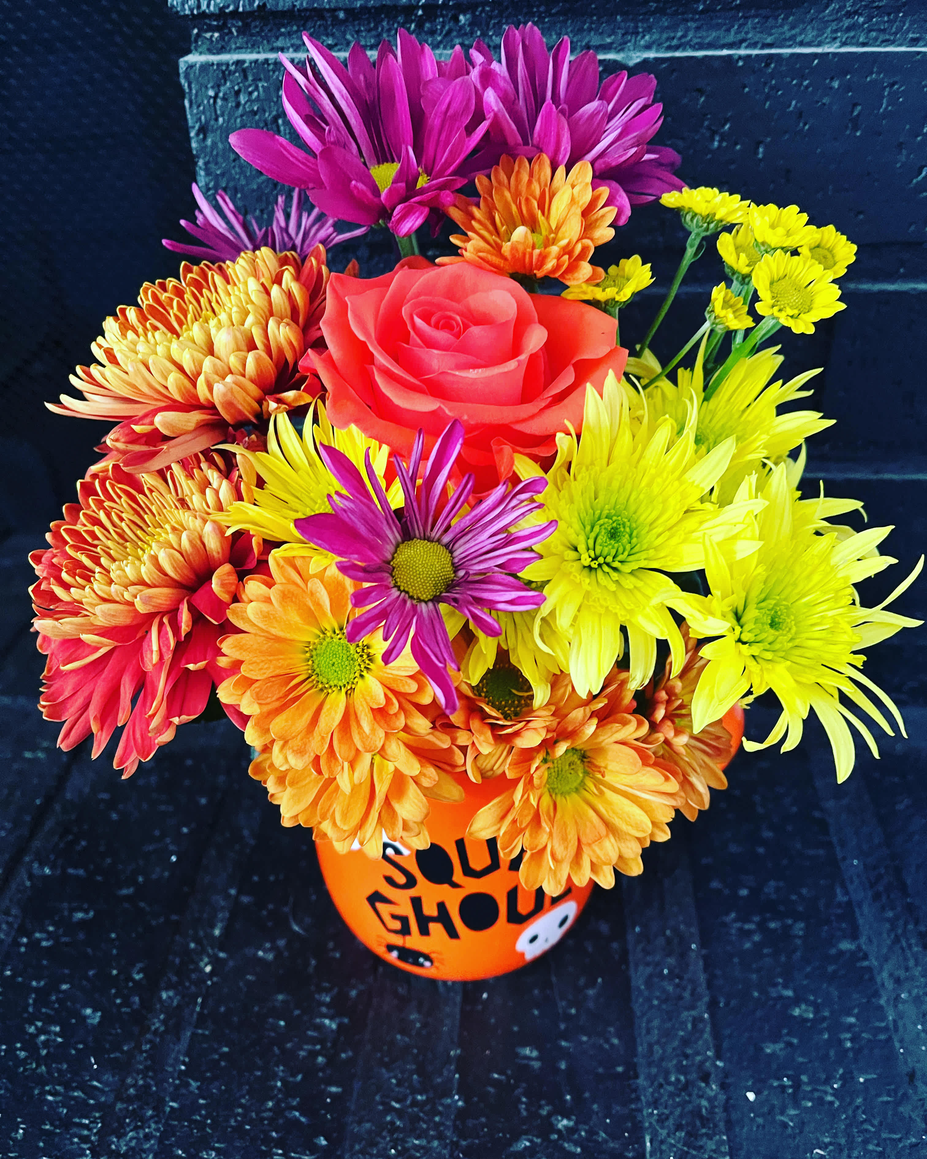 Bright mixed bouquet in an orange Halloween bucket with a pink rose