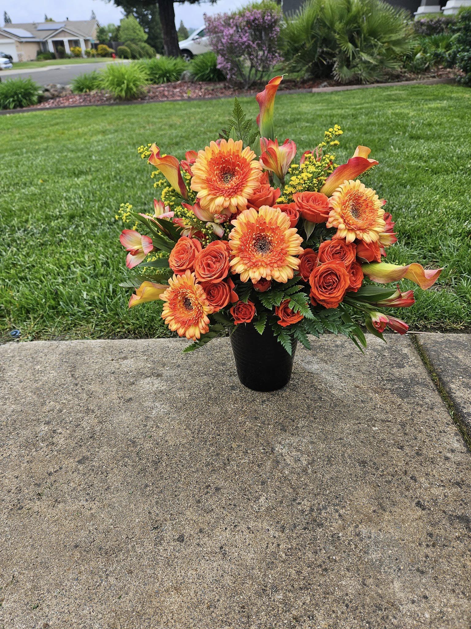Orange and yellow floral arrangement in a black vase