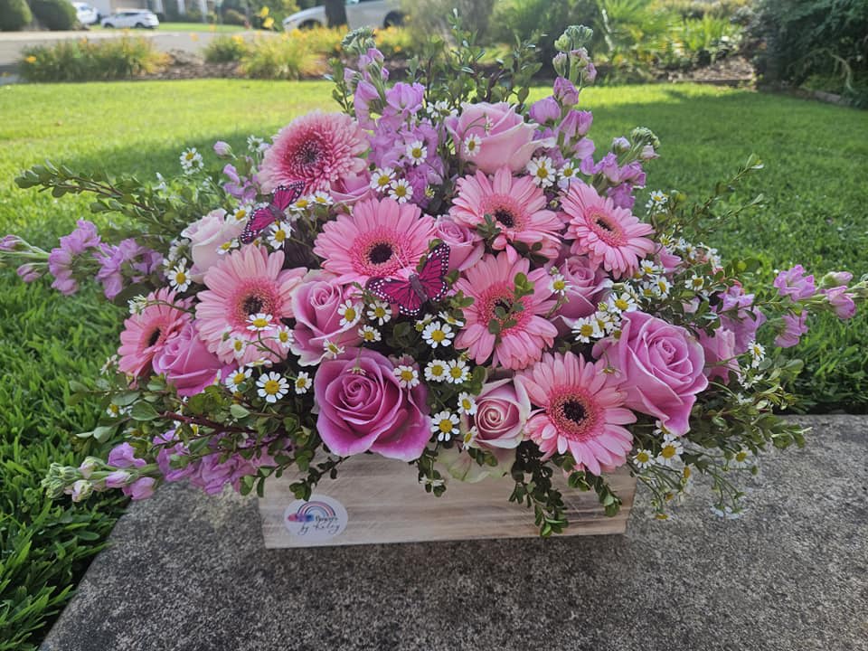 Pink gerbera daisies and roses in a wooden box with small daisies