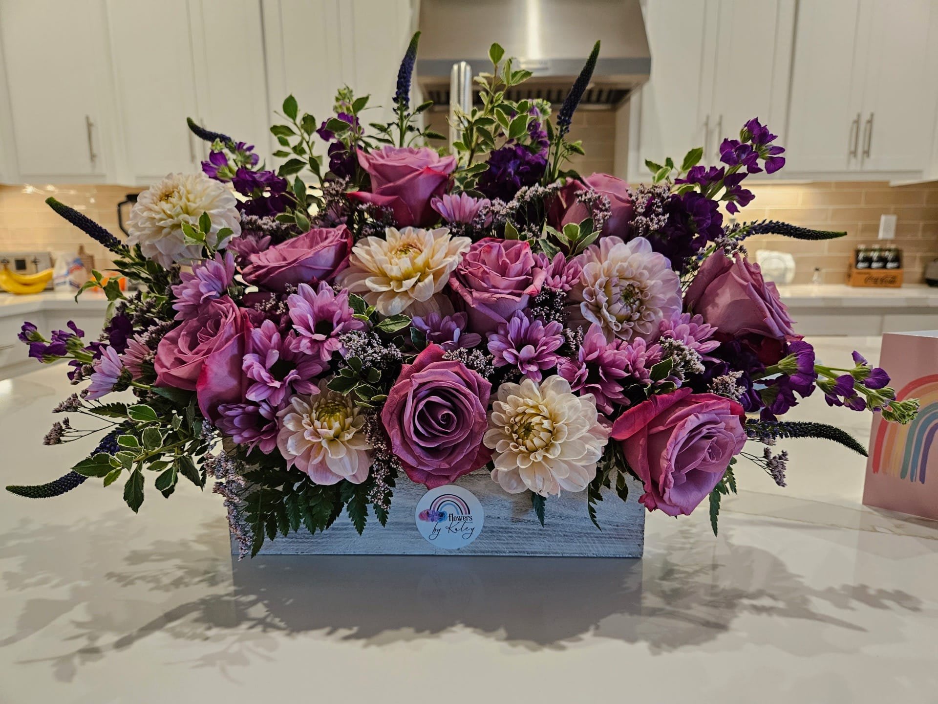 Pink and purple floral arrangement in a rectangular wooden box