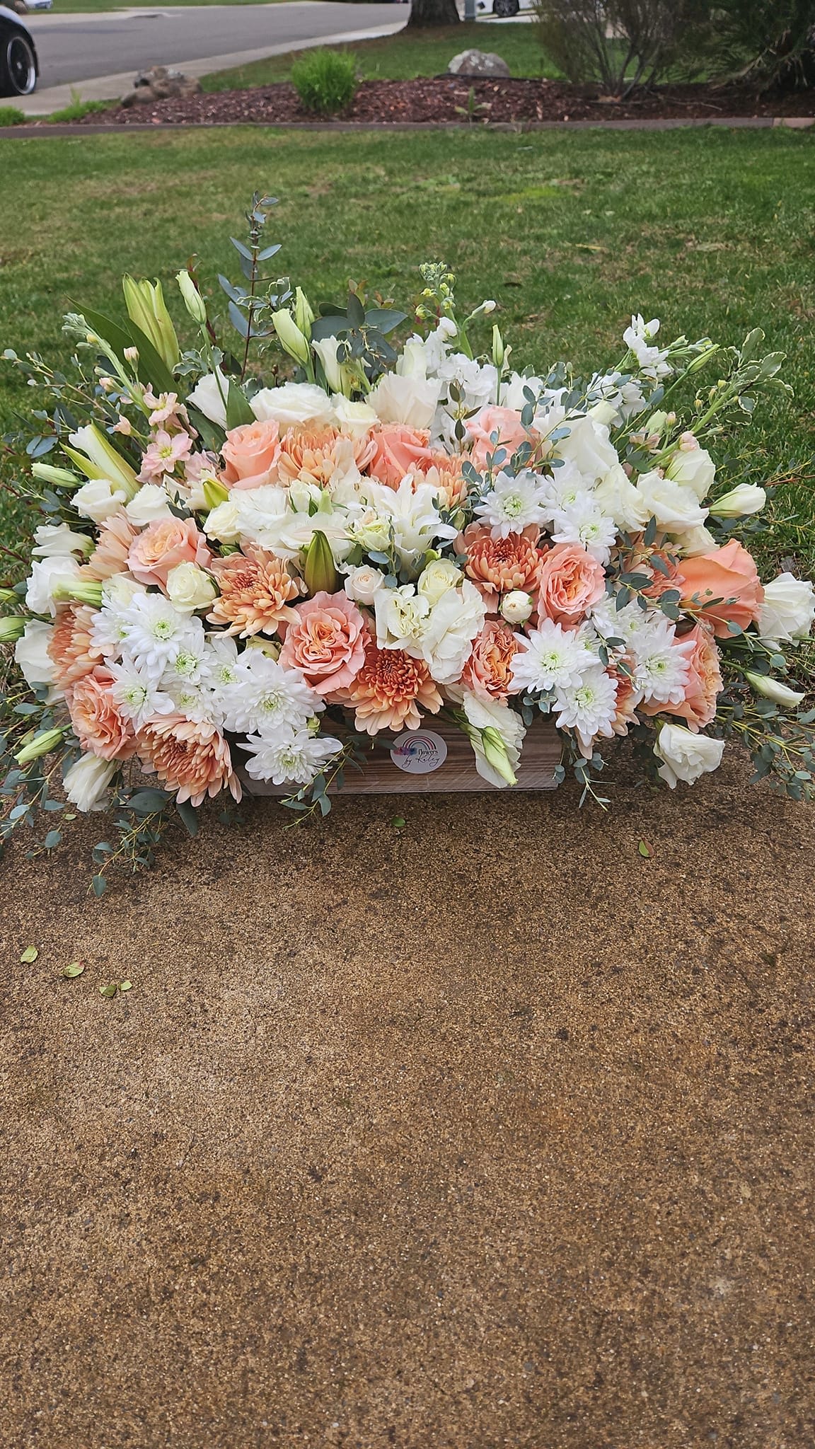 Large peach and white floral arrangement in a wooden container