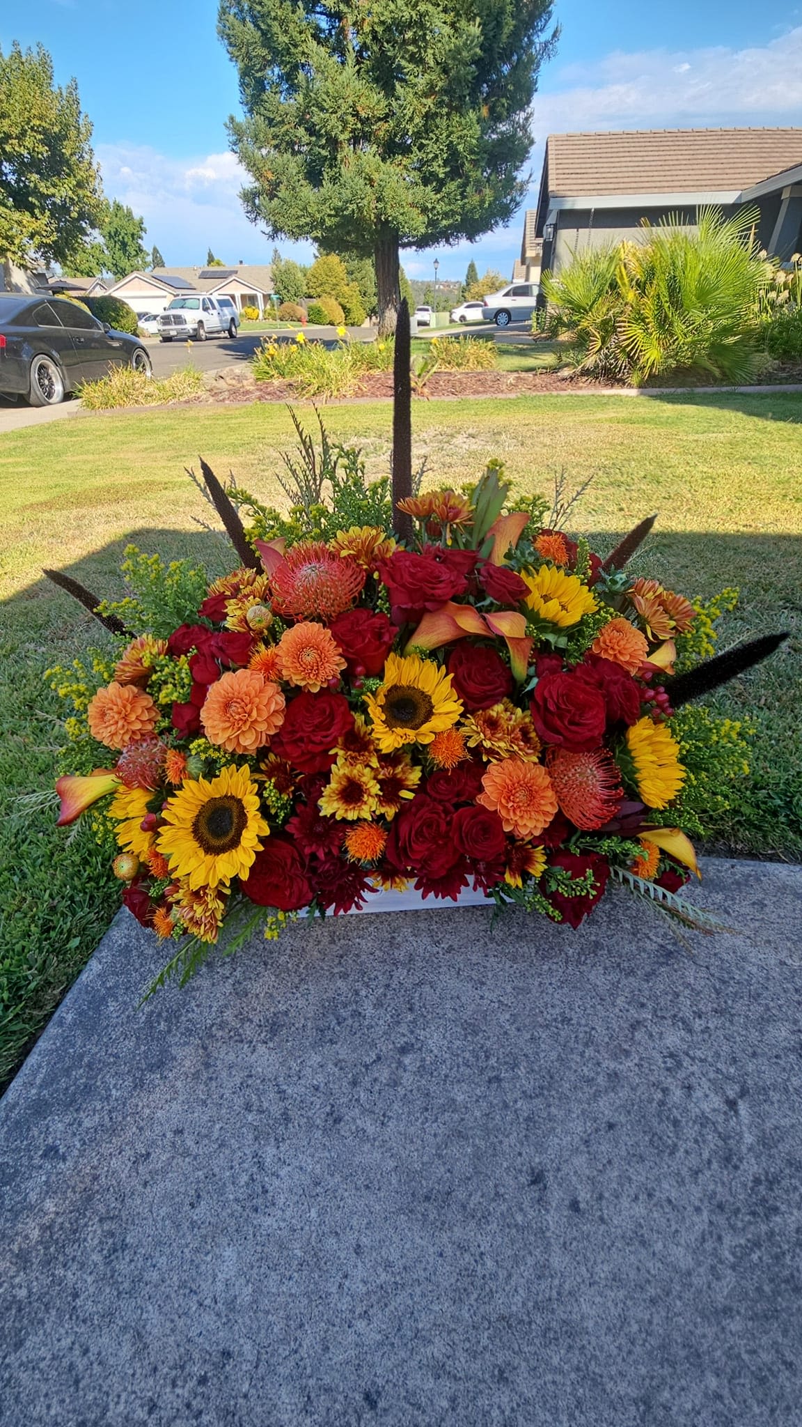 Large arrangement of red, orange, and yellow flowers in a low container