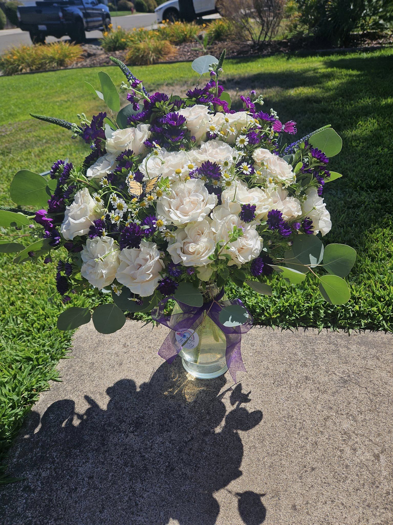 Bouquet of white roses and purple flowers in a glass vase