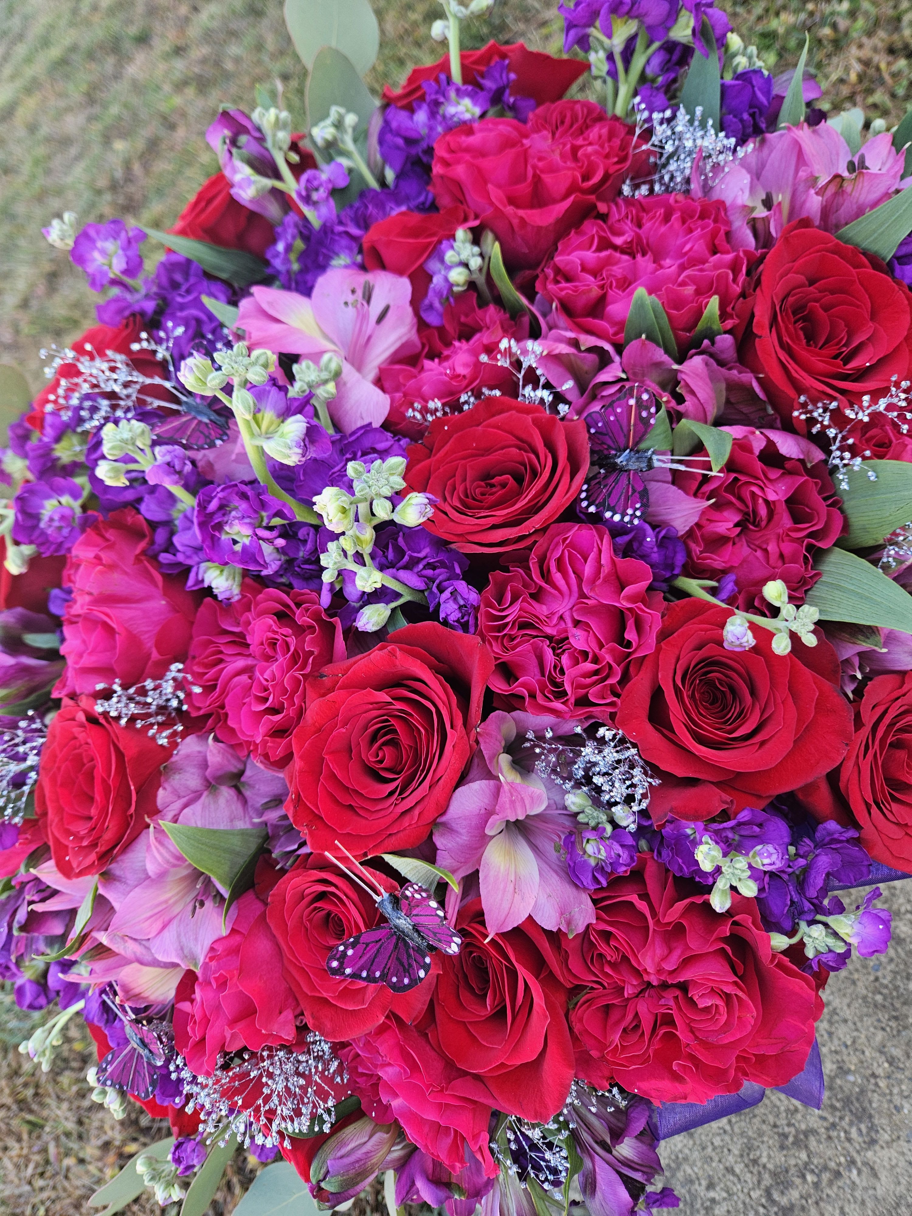 Bouquet of red and pink roses with purple flowers and butterfly accents