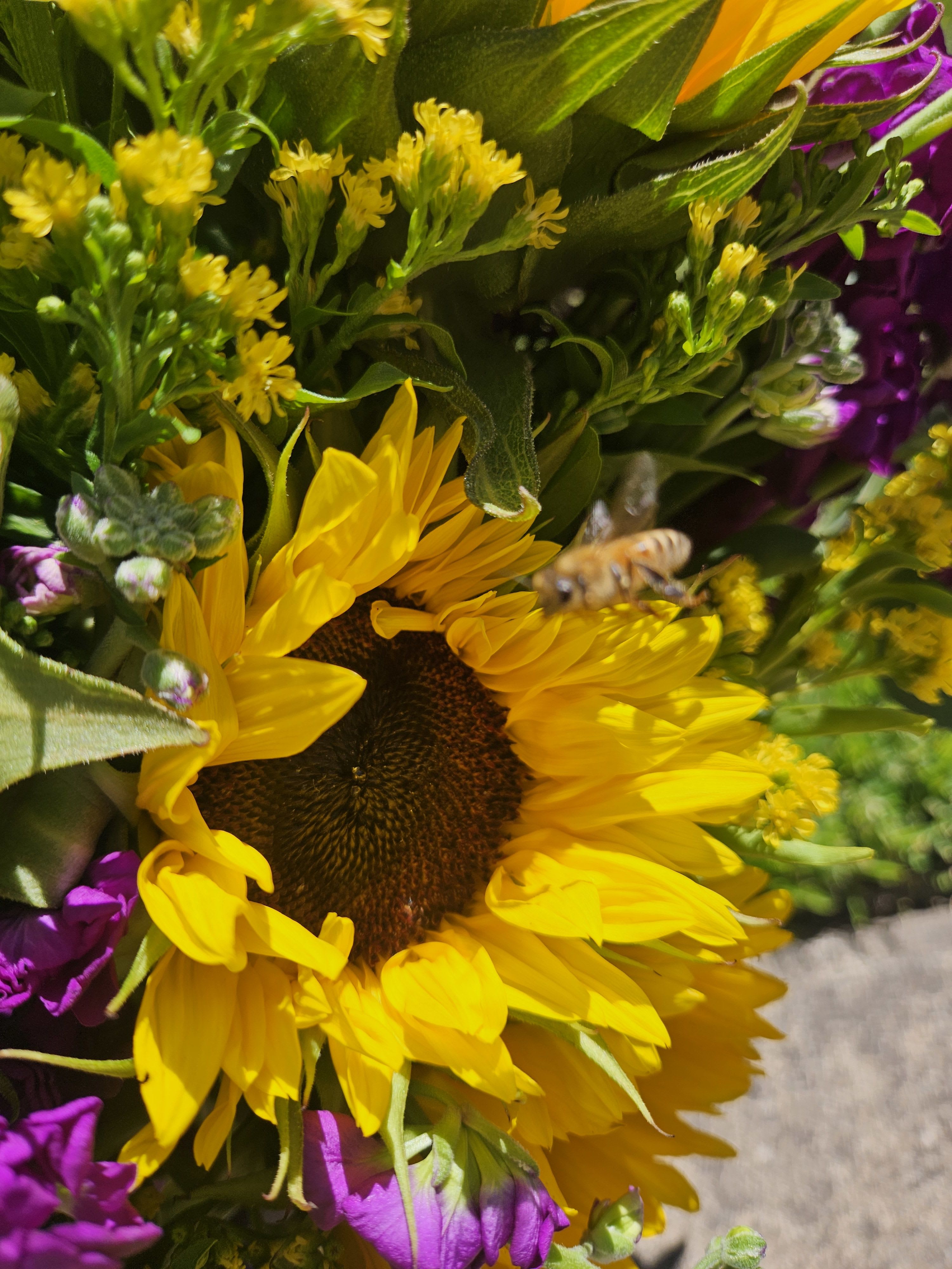 Close-up bouquet with a large yellow sunflower and purple flowers