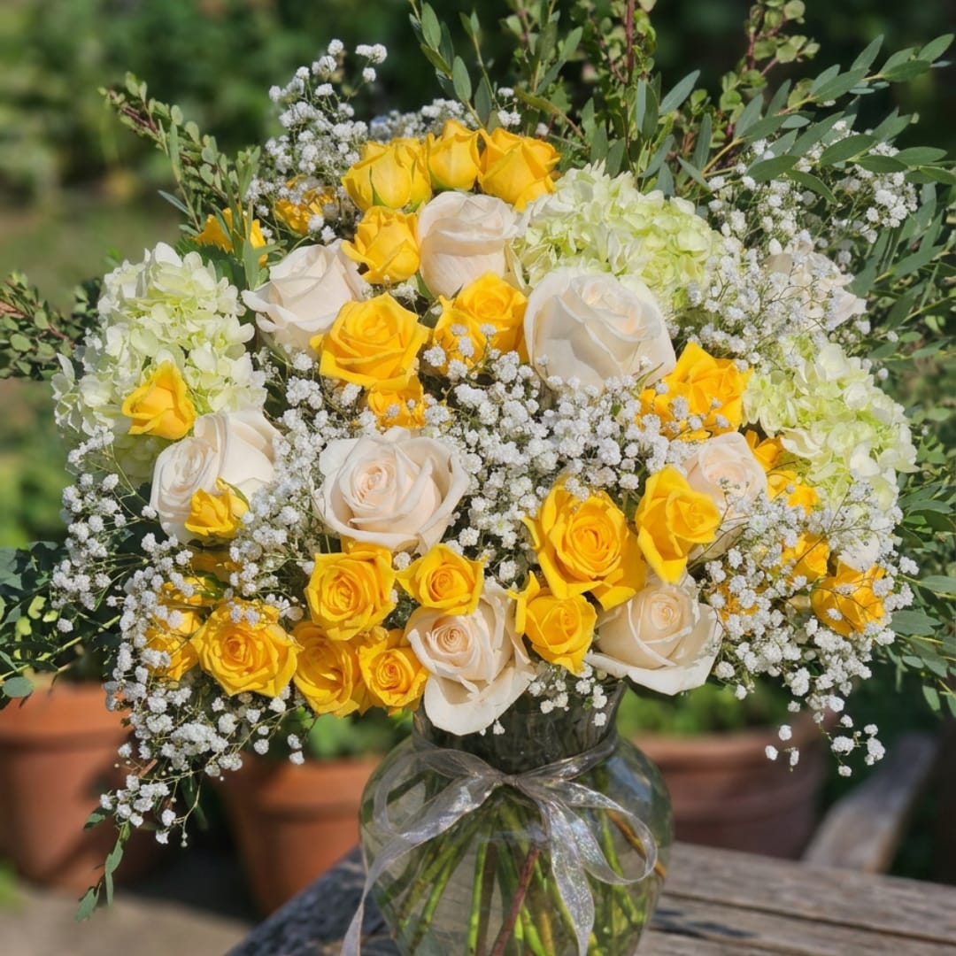 Bouquet of yellow and white roses in a glass vase with baby's breath