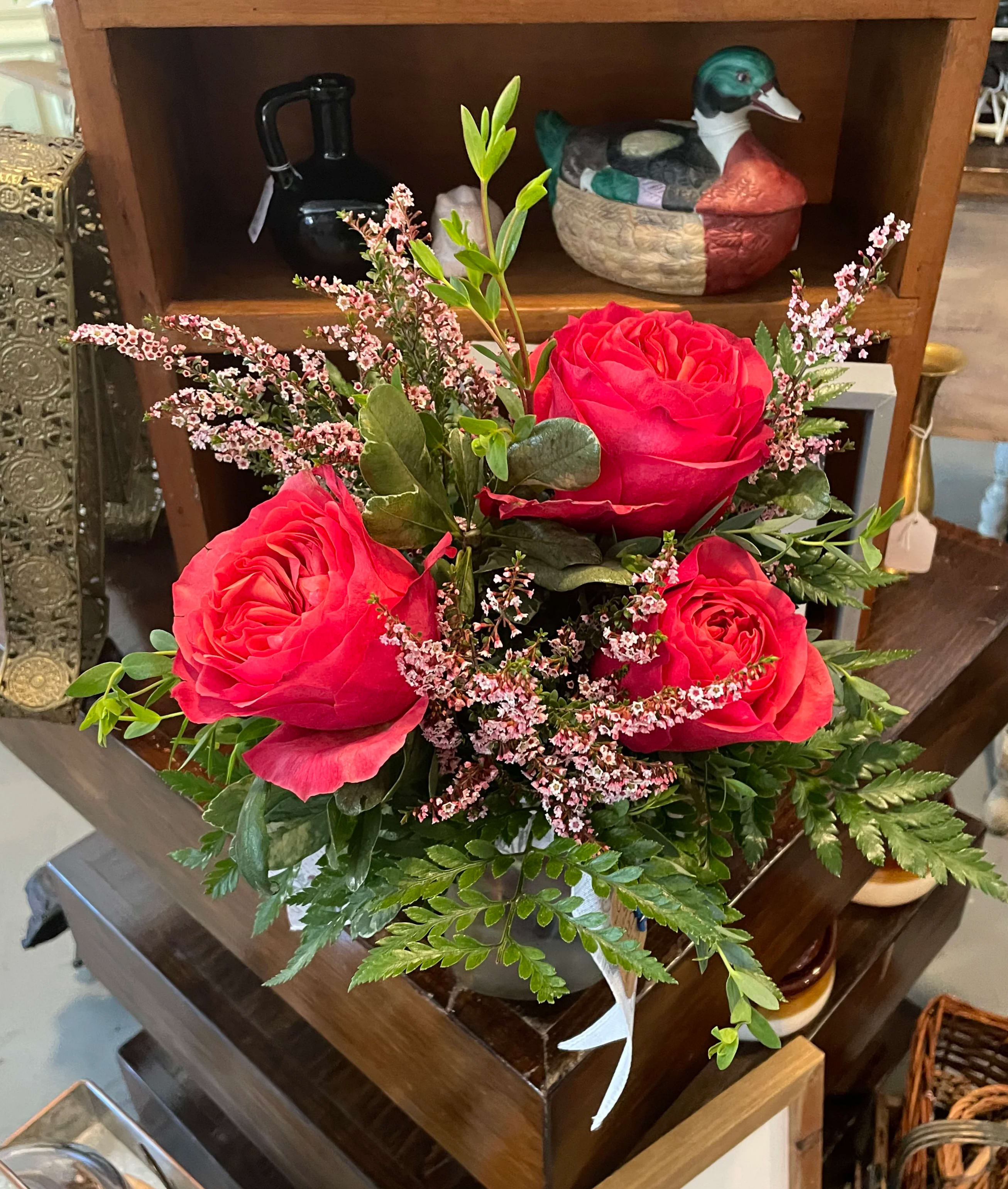 Stop and smell The Roses  - A small vintage style mason jar adorned with three hot pink garden like roses. A selection from our “pick me up” collection.  Filler may vary due to seasons