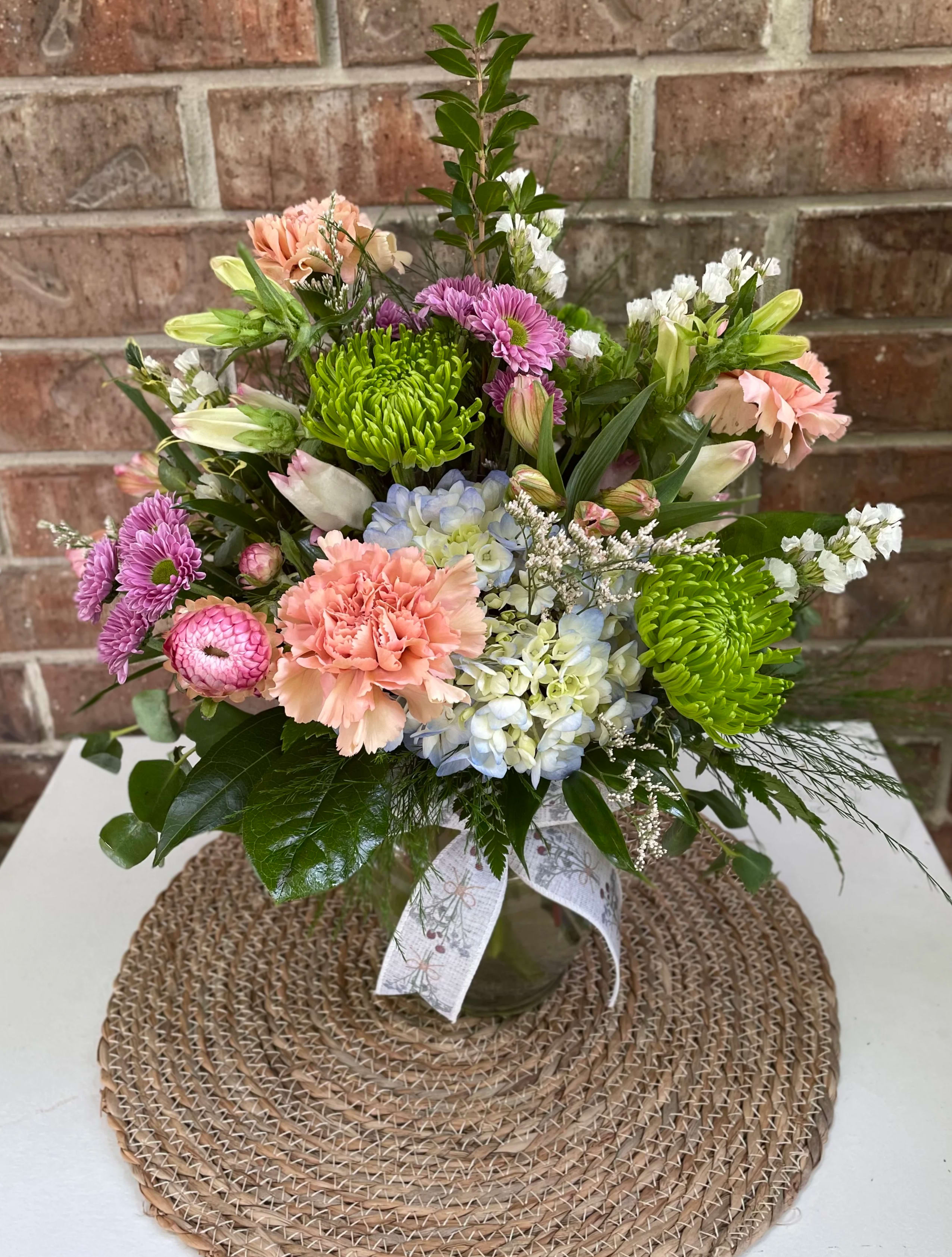 Mixed bouquet in a glass vase with pink, purple, blue, and green blooms