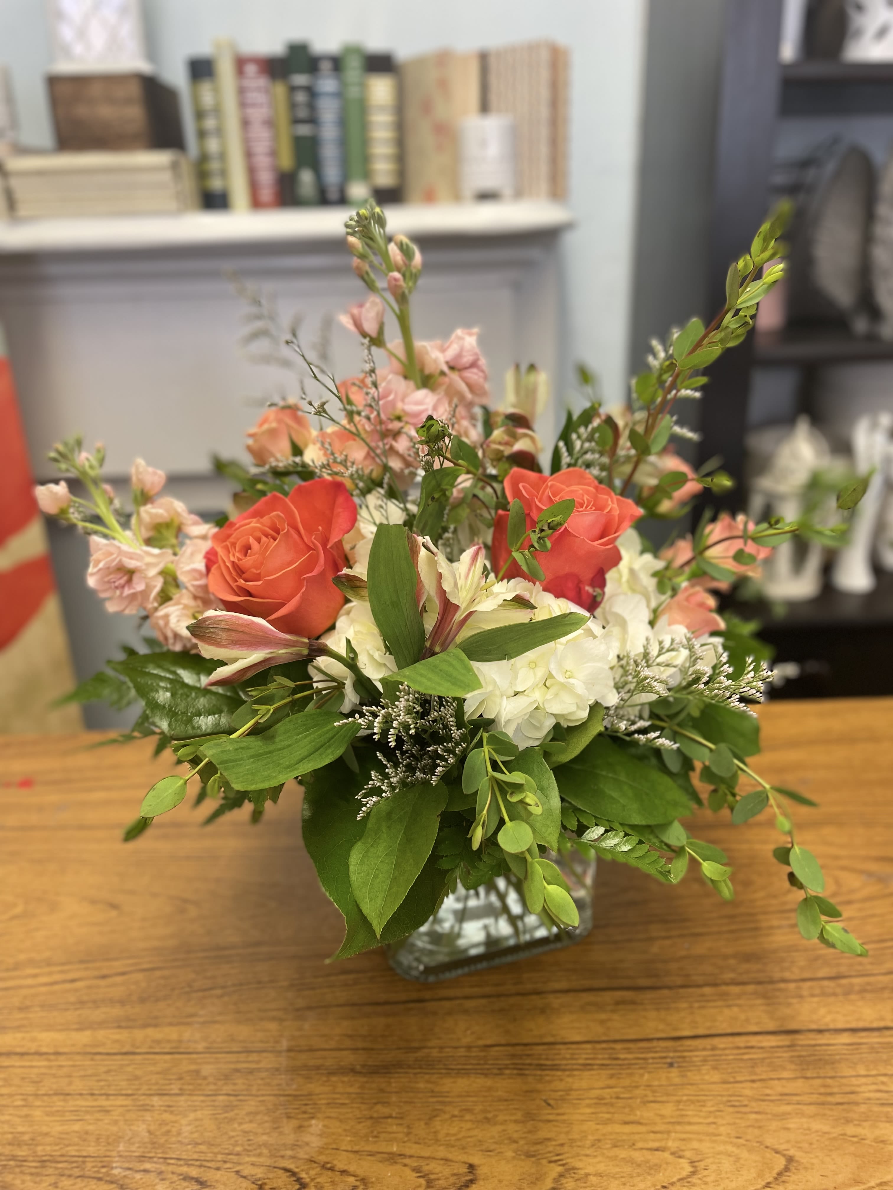 Mixed bouquet of coral roses, white hydrangeas, and pink blooms in a glass vase