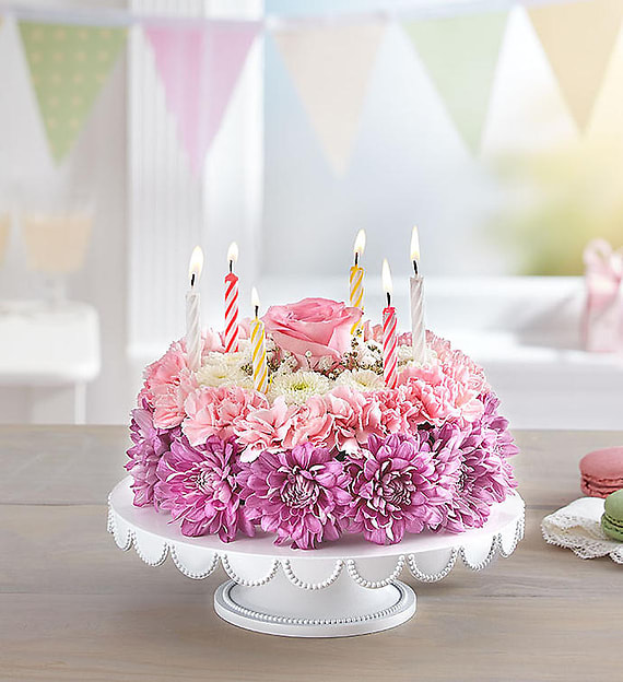 Birthday Wishes Flower Cake Pastel - No matter how you slice it, our Birthday Wishes Flower Cake will make their day! Handcrafted from carnations and poms in soft hues of pink, lavender, and white, it’s a one-of-a-kind centerpiece for a memorable celebration. Want to make the day even more special? A birthday balloon will take the fun to new heights! ****** VASE PLATE WILL VARY *********