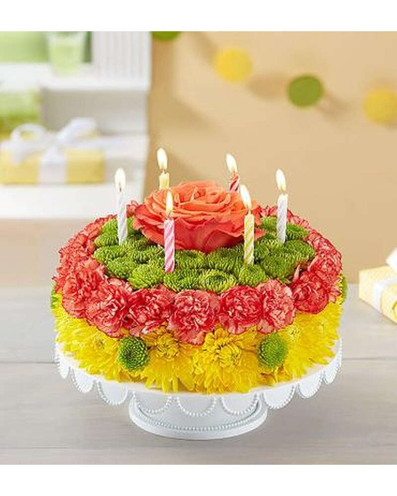 BIRTHDAY WISHES FLOWER CAKE- YELLOW - Be the reason their birthday is brighter! Our cheerful cake creation is crafted with a vibrant mix of blooms for a fun and lively birthday celebration. Served up on a pedestal stand and topped with candles, itâ€™s a truly original, festive way to celebrate somebody special. Take happy to new heights by adding a balloon to their gift.  ******* VASE PLATE WILL VARY ******