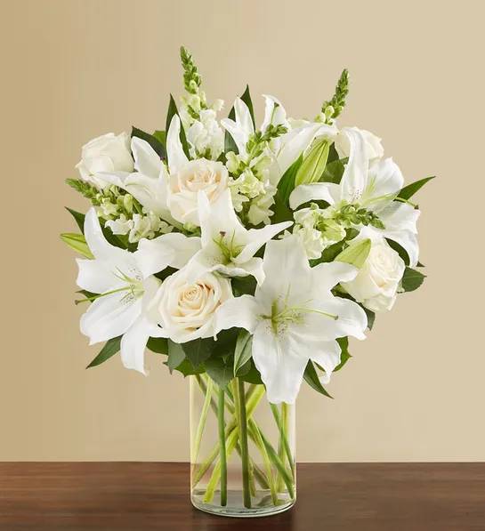 Classic All White Arrangement - White flowers have a timeless elegance, which is captured in our luxurious all-white arrangement. A soft yet poignant mix of roses, lilies and snapdragons is hand-gathered by our expert florists with touches of lush greenery inside a stylish cylinder vase. What more beautiful gift to express your love, thanks, appreciation, support—whatever is on your mind and in your heart. ** VASE WILL VARY**