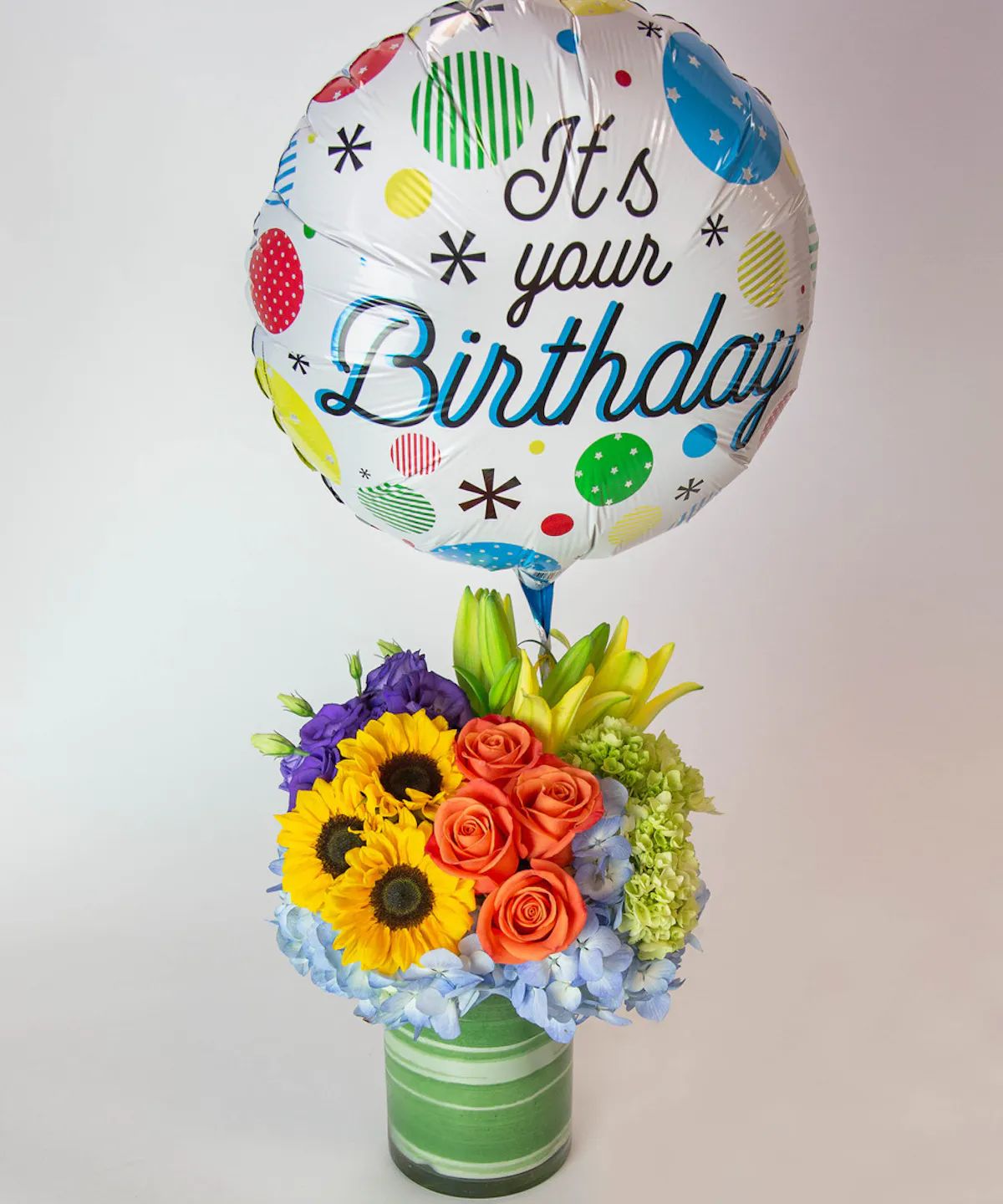 BIRTHDAY BLOOMS - What better way to say "Happy Birthday" than with our Birthday Blooms arrangement? This beautiful, colorful bouquet is filled with hydrangea, sunflowers, roses, asiatic lilies, and lisianthus in a tall cylinder glass leaf-lined vase, and comes with a fun birthday mylar balloon to add the finishing touch to your birthday wishes!   **** PLEASE NOTE BALLOON DESIGN AND/ OR COLORS MAY VARY***