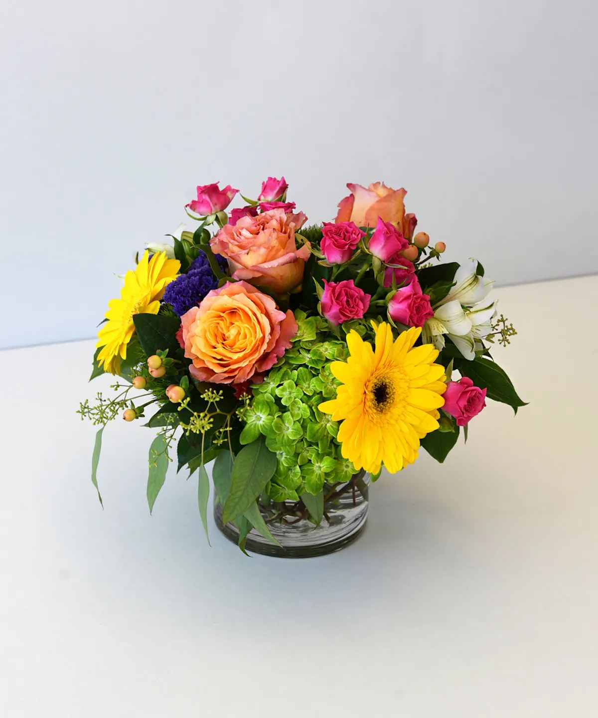 BLOSSOMS OF JOY - Give someone a surprise with this charming vase of flowers overflowing with cheerful roses, gerbera daisies, hydrangea, alstroemeria, statice and more.  Just looking at it will fill them with joy.