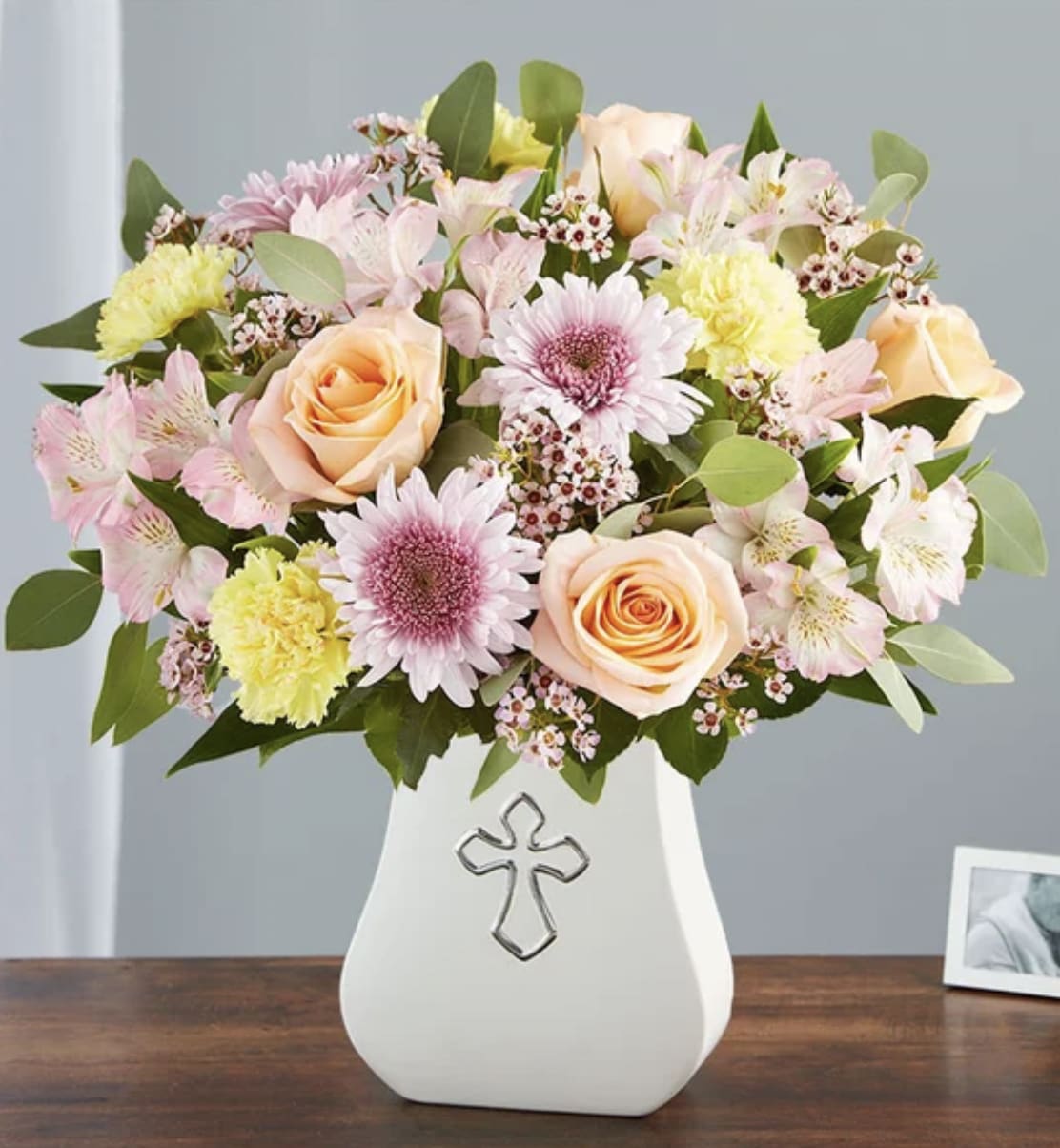 Sacred Blessings Pastel - Our serene pastel arrangement is a lovely way to honor someone special. Gathered with peach, lavender, pink and yellow blooms, it’s elegantly arranged in our Sacred Blessings vase, featuring a silver-embossed cross: an eternal symbol of hope. This soothing floral tribute brings peace to those mourning a loss.