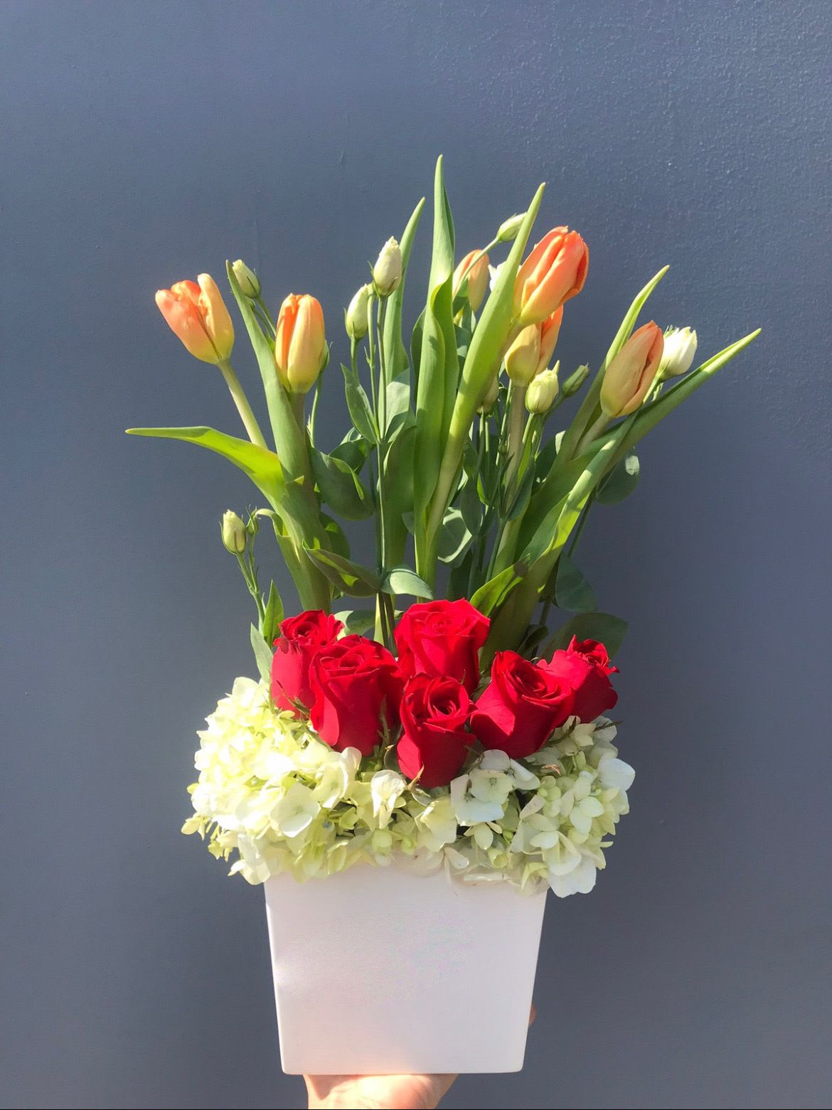 Spring Romance Bloom Box - The "Spring Romance Bloom Box" is a charming floral arrangement that brings together the elegance of soft peach tulips, the passion of classic red roses, and the delicate beauty of white hydrangeas. Nestled in a sleek white box, this arrangement captures the essence of spring love and fresh beginnings. Ideal for birthdays, romantic gestures, or brightening someone’s day, this design radiates warmth and sophisticated charm.
