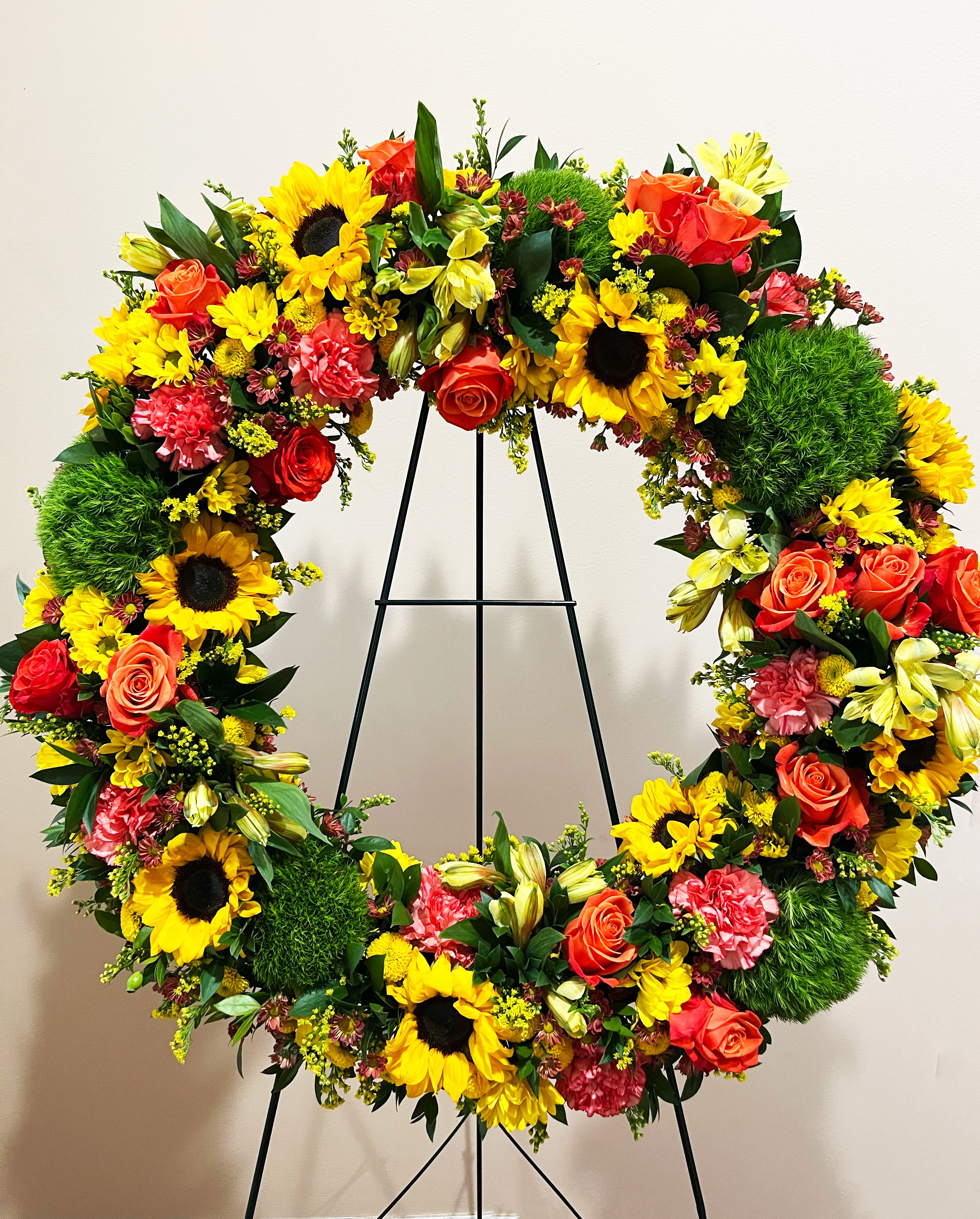 22" Autumnal Memories Wreath - AUTUMNAL MEMORIES WREATH  Our Autumnal Memories Wreath captures the season with fresh, harvest hues. This wreath is designed with sunflowers, roses, and dianthus to share thoughtful messages for sympathy or any occasion.