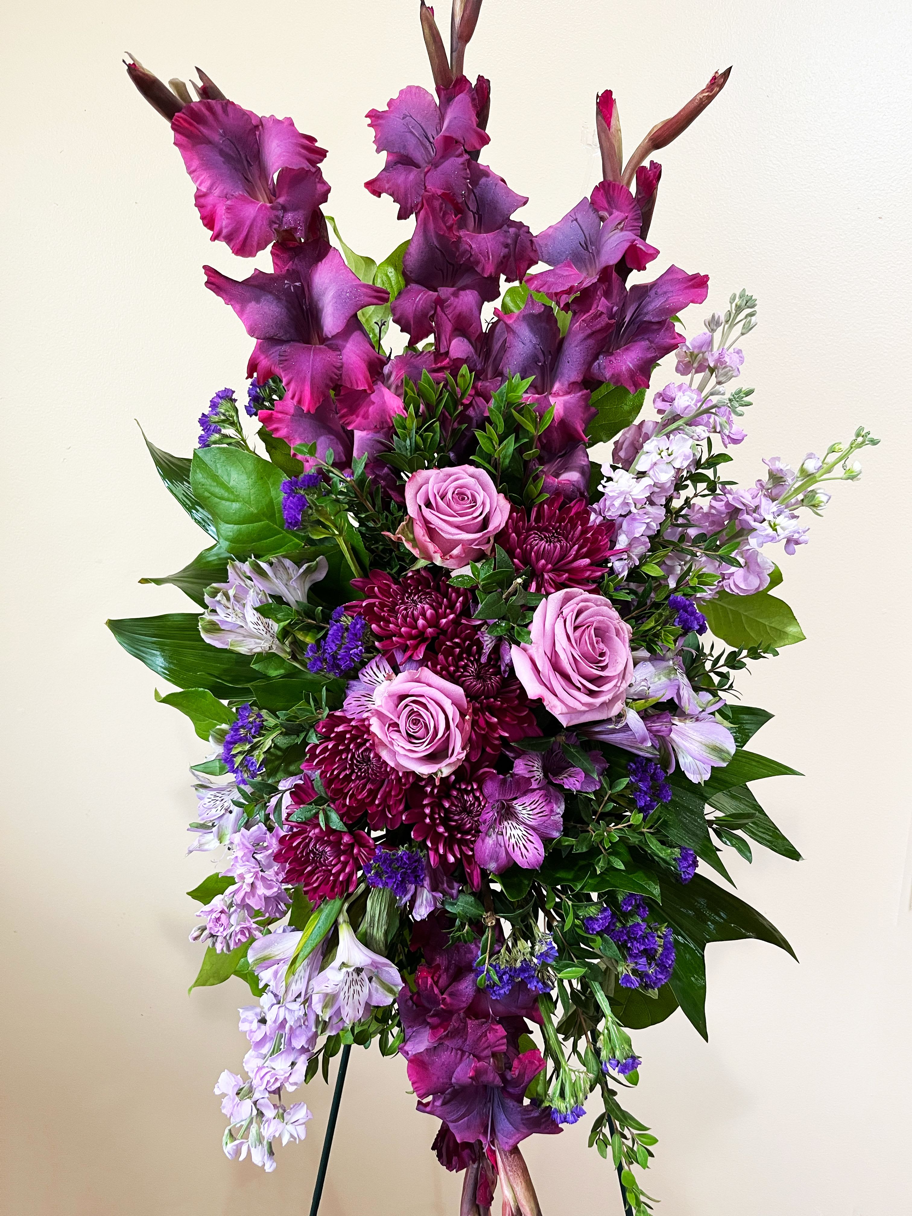 Lavender Reflections Spray - Take a walk through the garden of memories with this lush spray of lavender and purple blooms, accented with fresh green ti leaves. It's a joyful expression of sympathy sure to be appreciated.