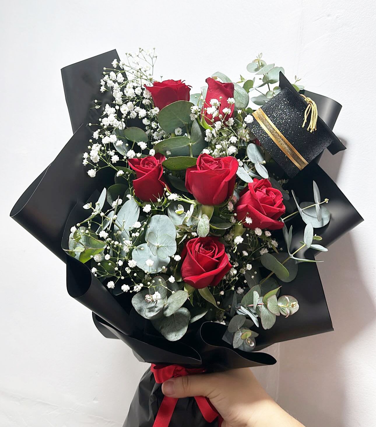 6 Red Roses Grad Arranged - 6 Red Roses Grad Arranged with accents of eucalyptus and baby breath. *** GRAD HAT DESIGN WILL VARY***