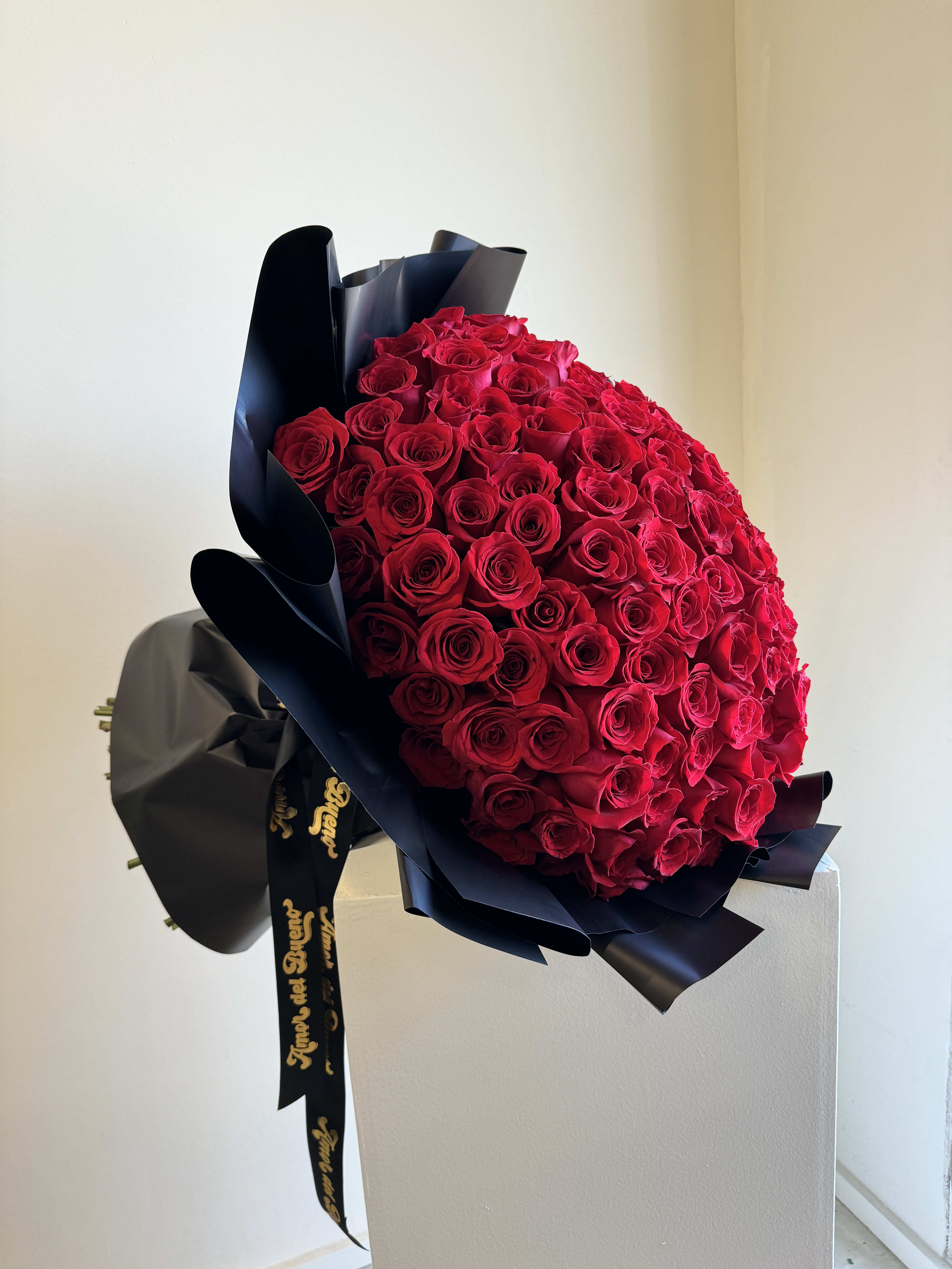 Large bouquet of red roses wrapped in black paper with a ribbon