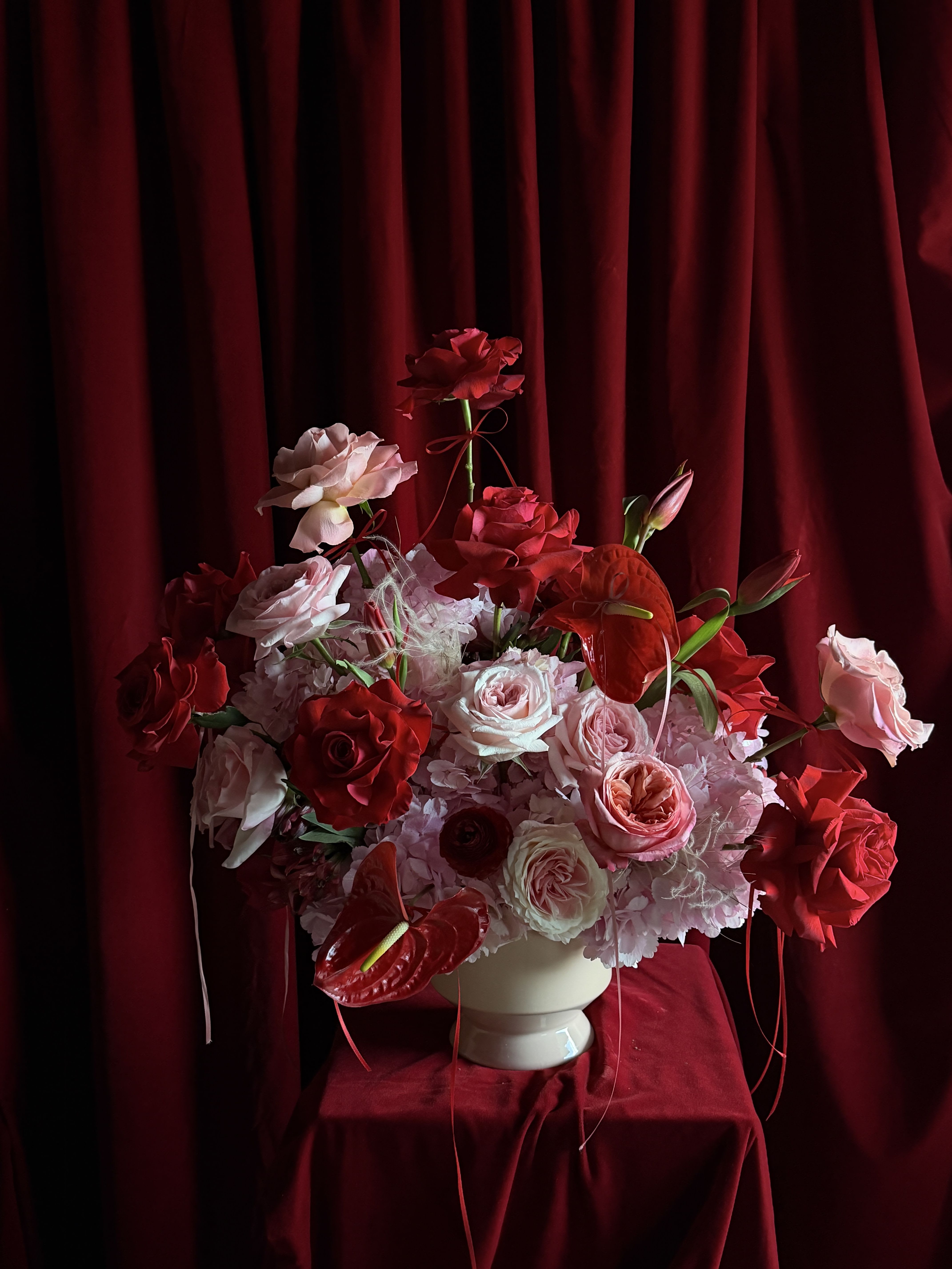 Red and pink rose arrangement in a white vase
