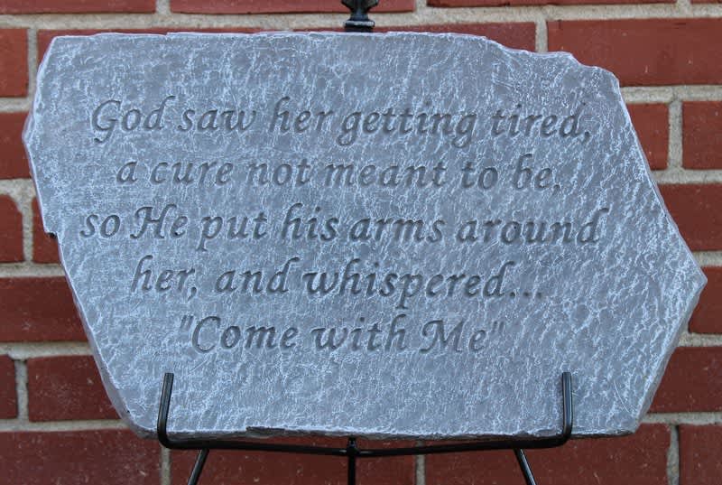 Engraved stone plaque with a religious quote on a metal stand