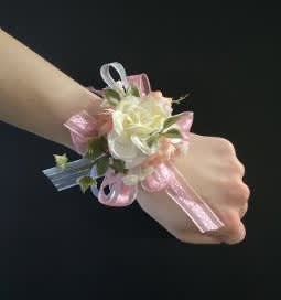 White rose wrist corsage with pink ribbon on a wrist