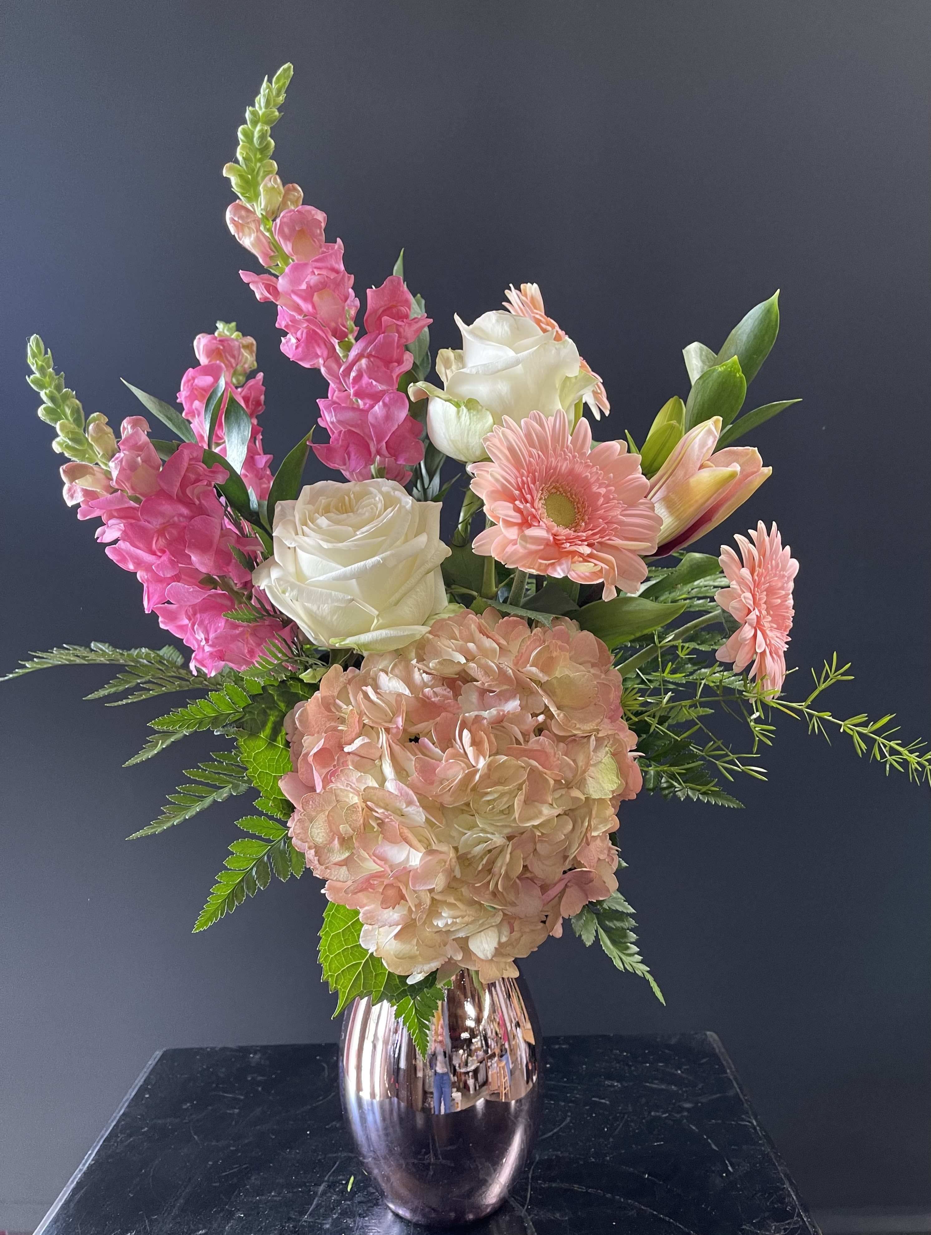 Arrangement of pink and white flowers with hydrangea and roses in a metallic rose-gold vase