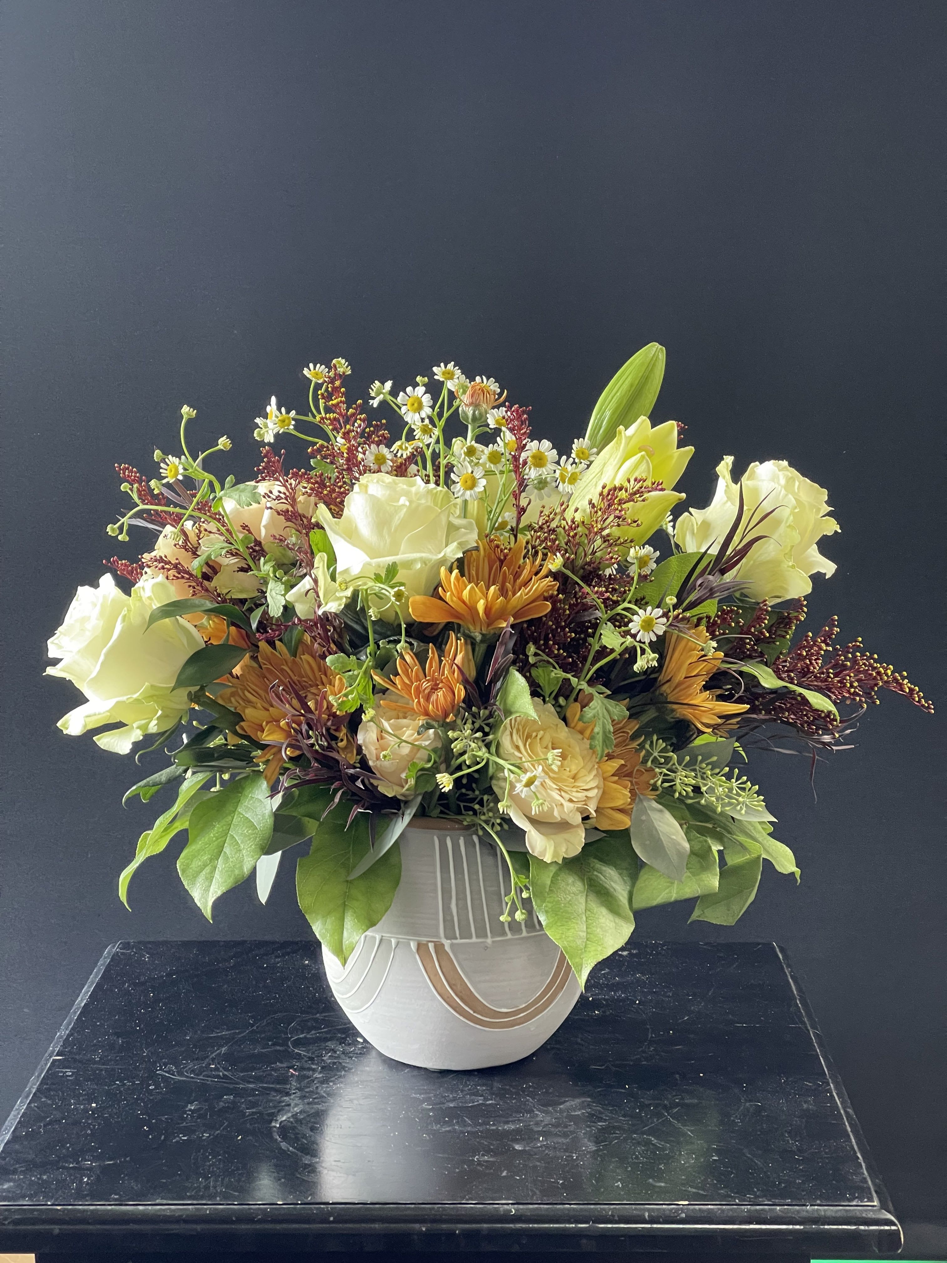 Mixed bouquet in a white ceramic vase with cream and orange flowers