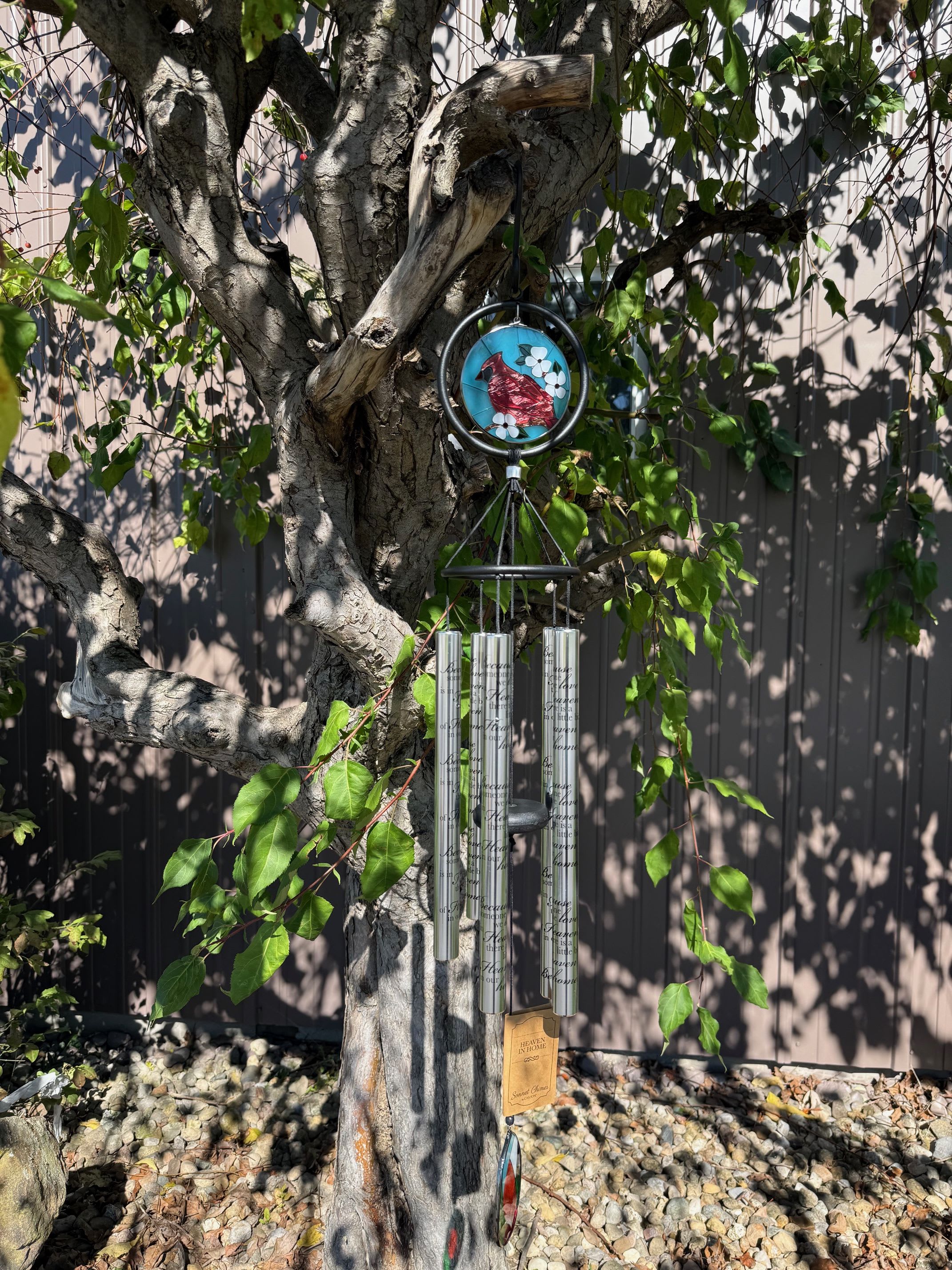 Wind chime hanging from a tree branch with a small bird ornament