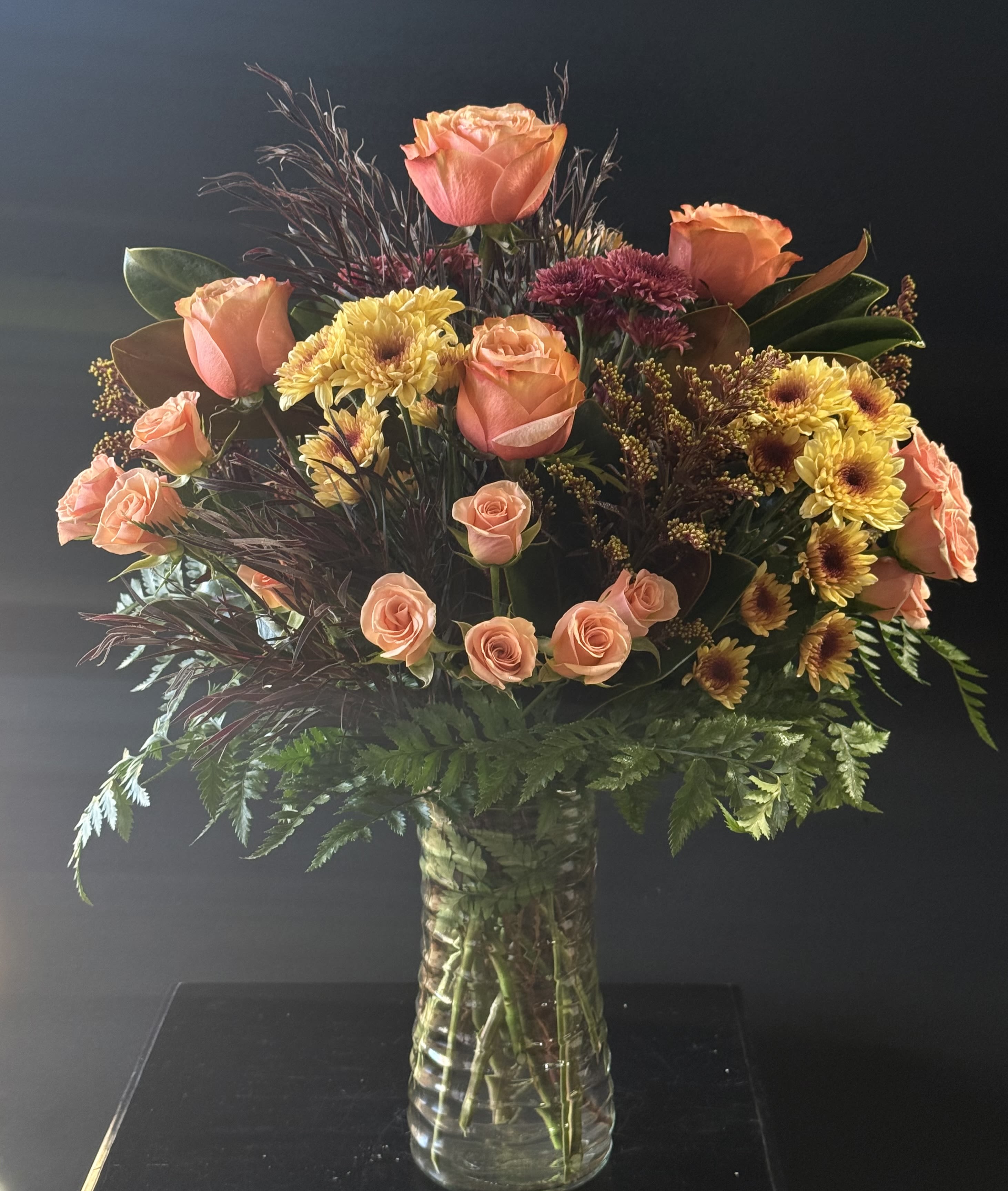 Bouquet of peach roses and yellow chrysanthemums in a clear glass vase