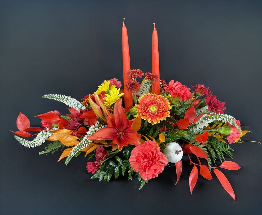 Give Thanks - Elevate your holiday decor with a beautiful fresh floral centerpiece of lilies, carnations, daisies, veronicas, and preserved Italian ruscus leaves. Arrangement includes 2 functional wax pillar candles.