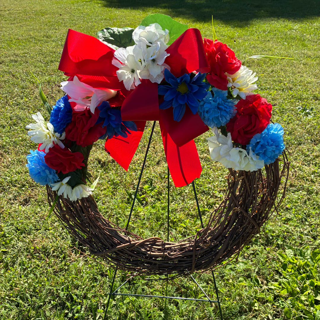 Floral wreath with red, white, and blue flowers and a large red bow