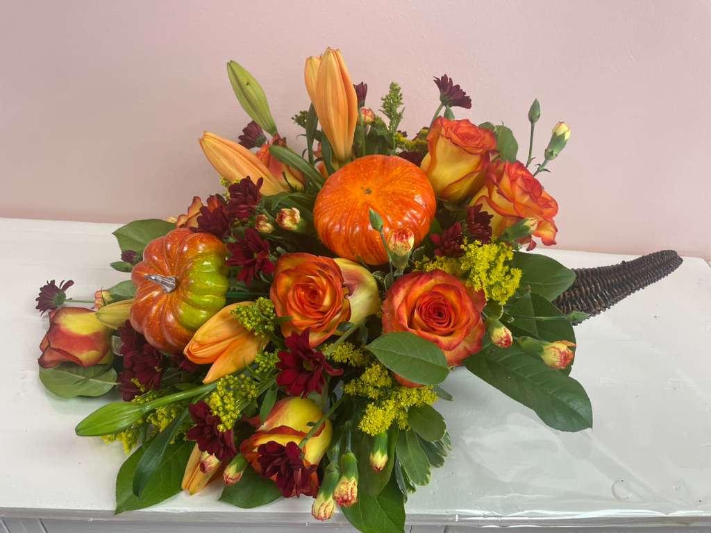 Orange roses and lilies arranged with decorative pumpkins