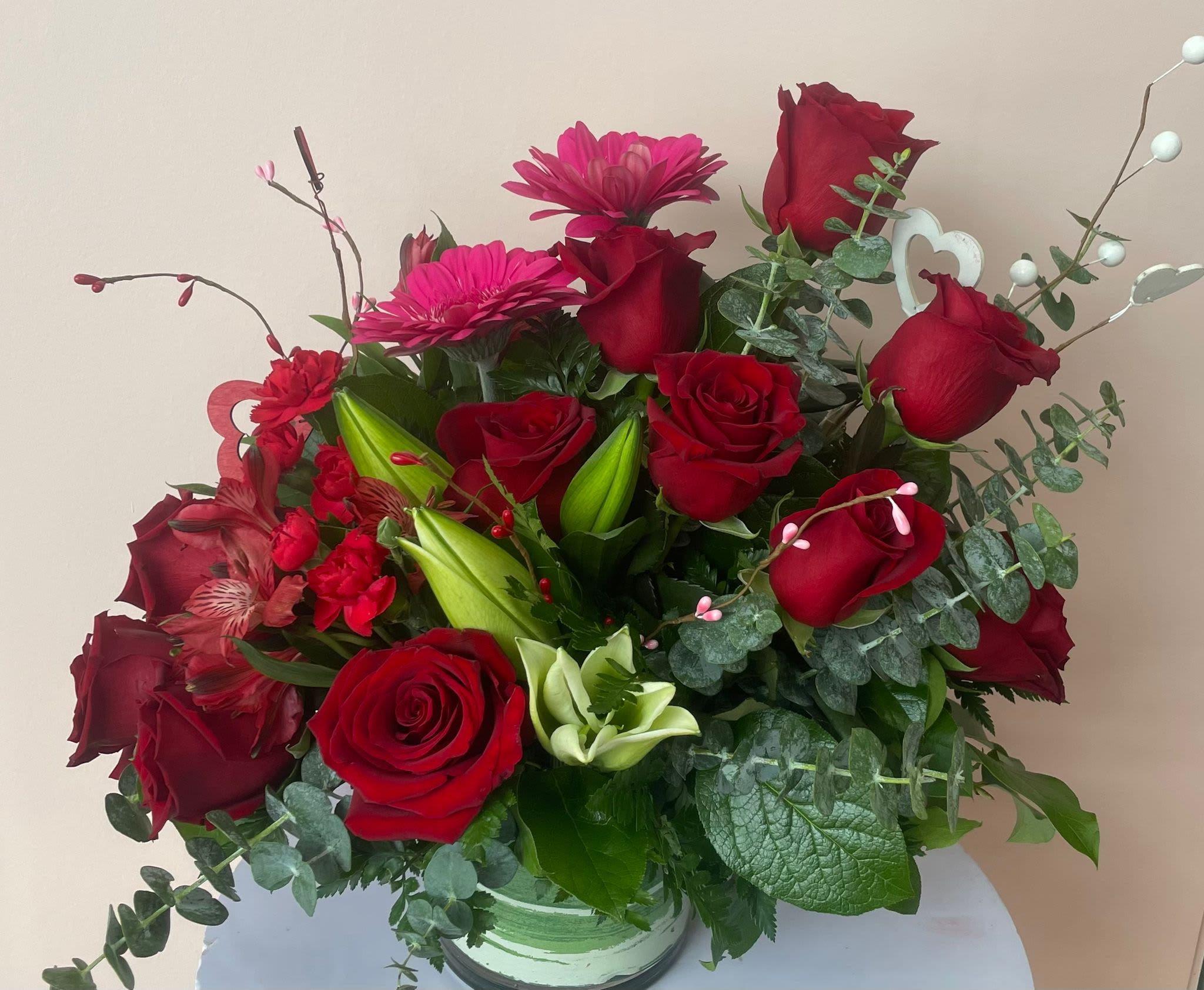 Bouquet of red roses and pink gerbera daisies in a glass vase