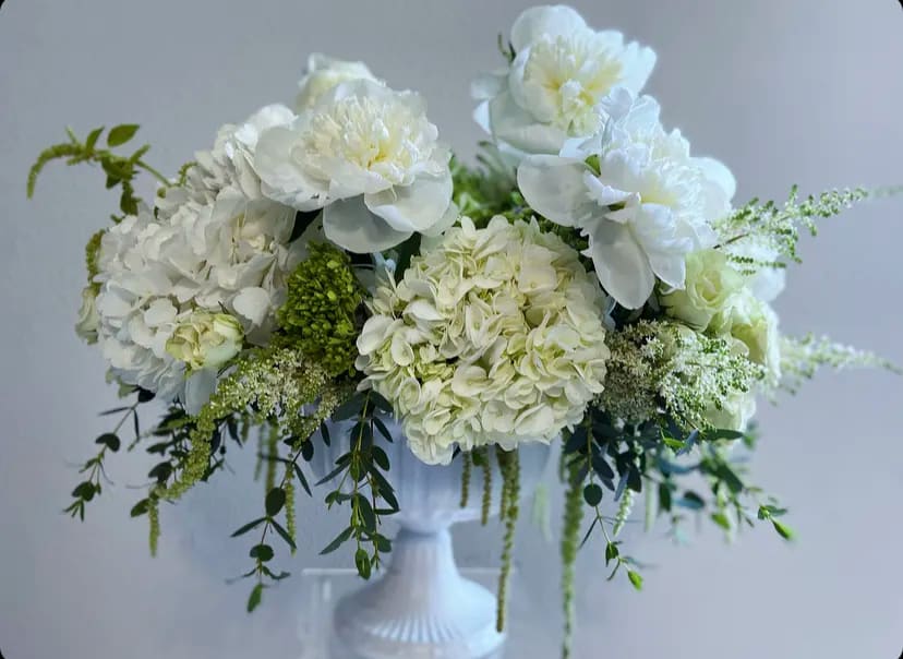 White floral arrangement in a white pedestal vase