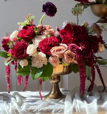 Arrangement of red, blush, and white roses in a gold vase