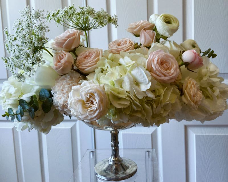 Blush roses and cream hydrangeas in a silver pedestal vase