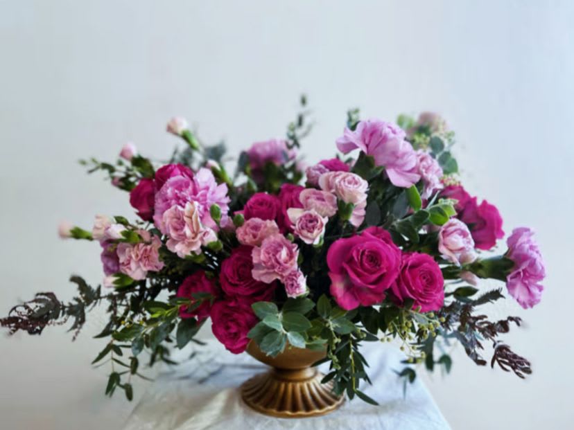 Pink roses and carnations in a gold pedestal vase