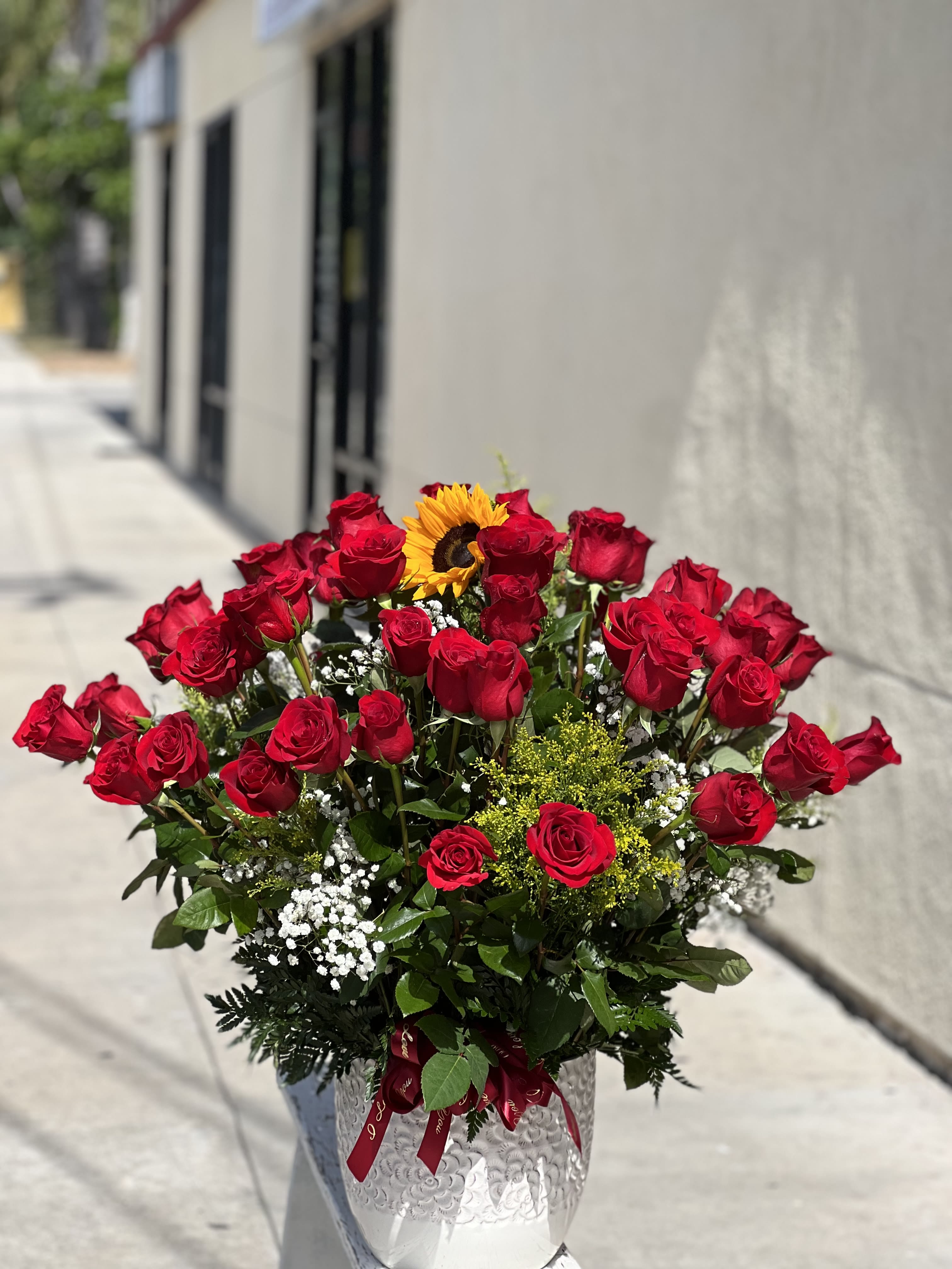 Bouquet of red roses with a sunflower in a silver vase