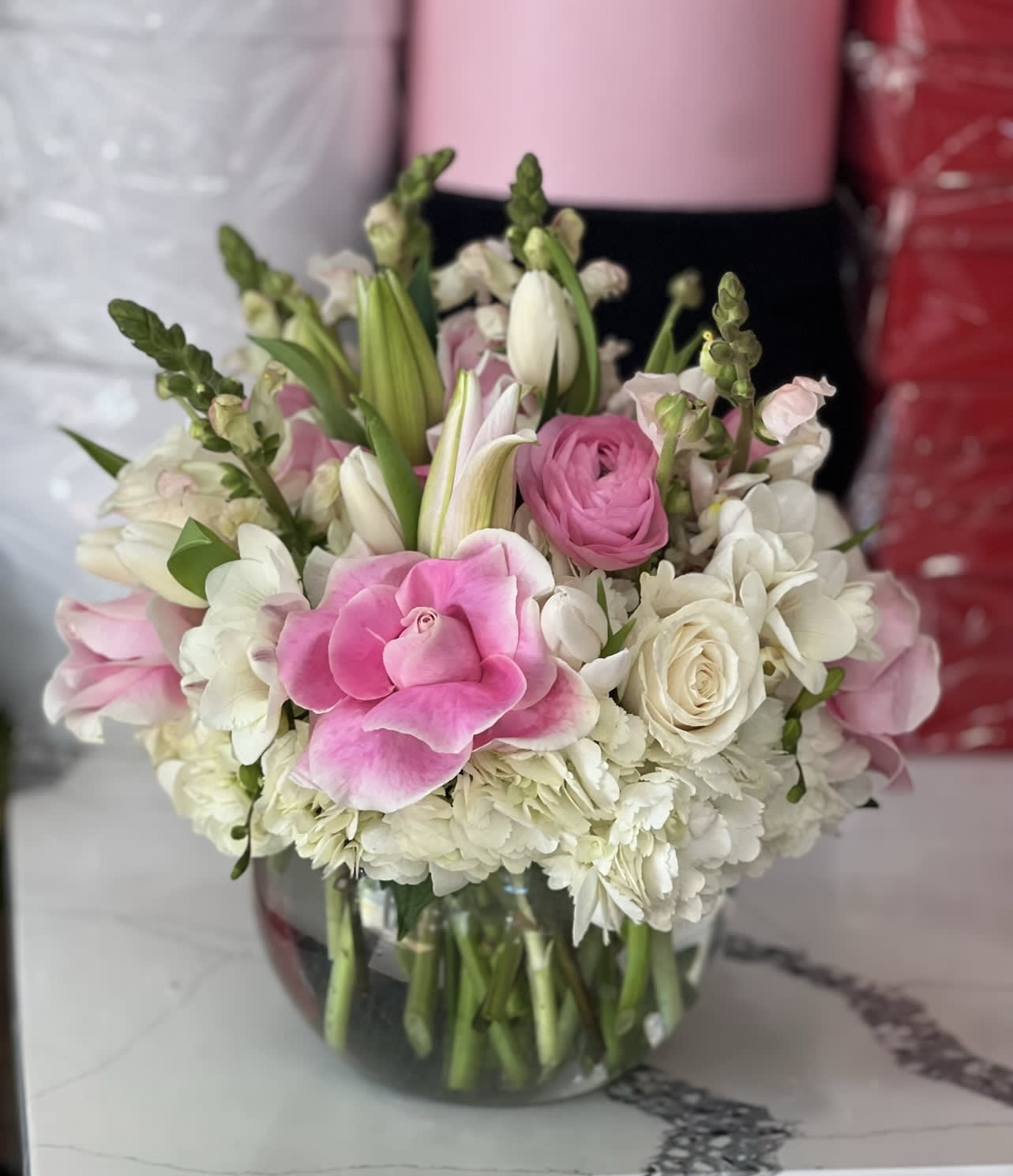 Pink and white flowers arranged in a clear glass vase